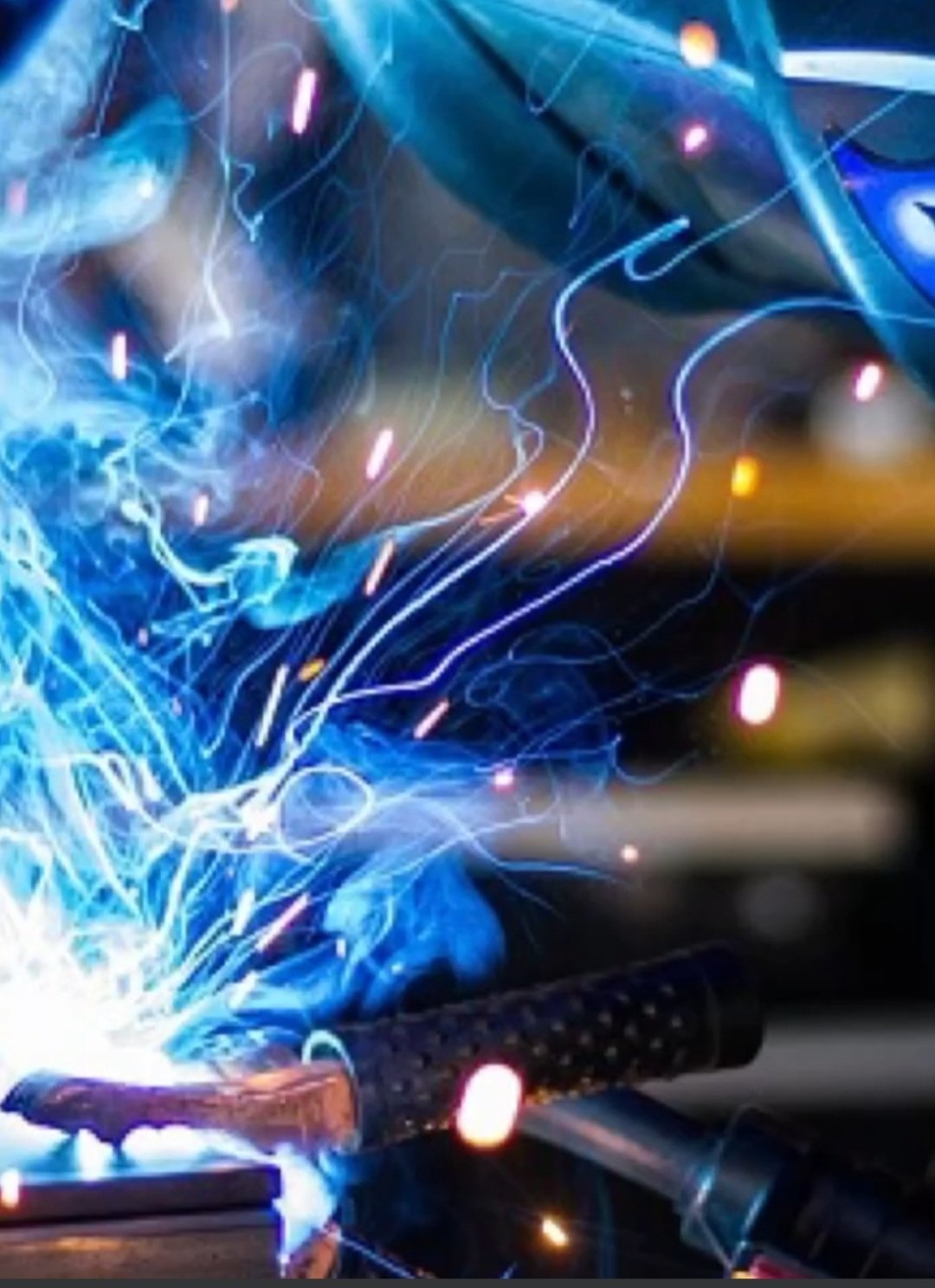 Close-up of bright blue welding sparks and flames against a dark background, highlighting industrial metalwork.