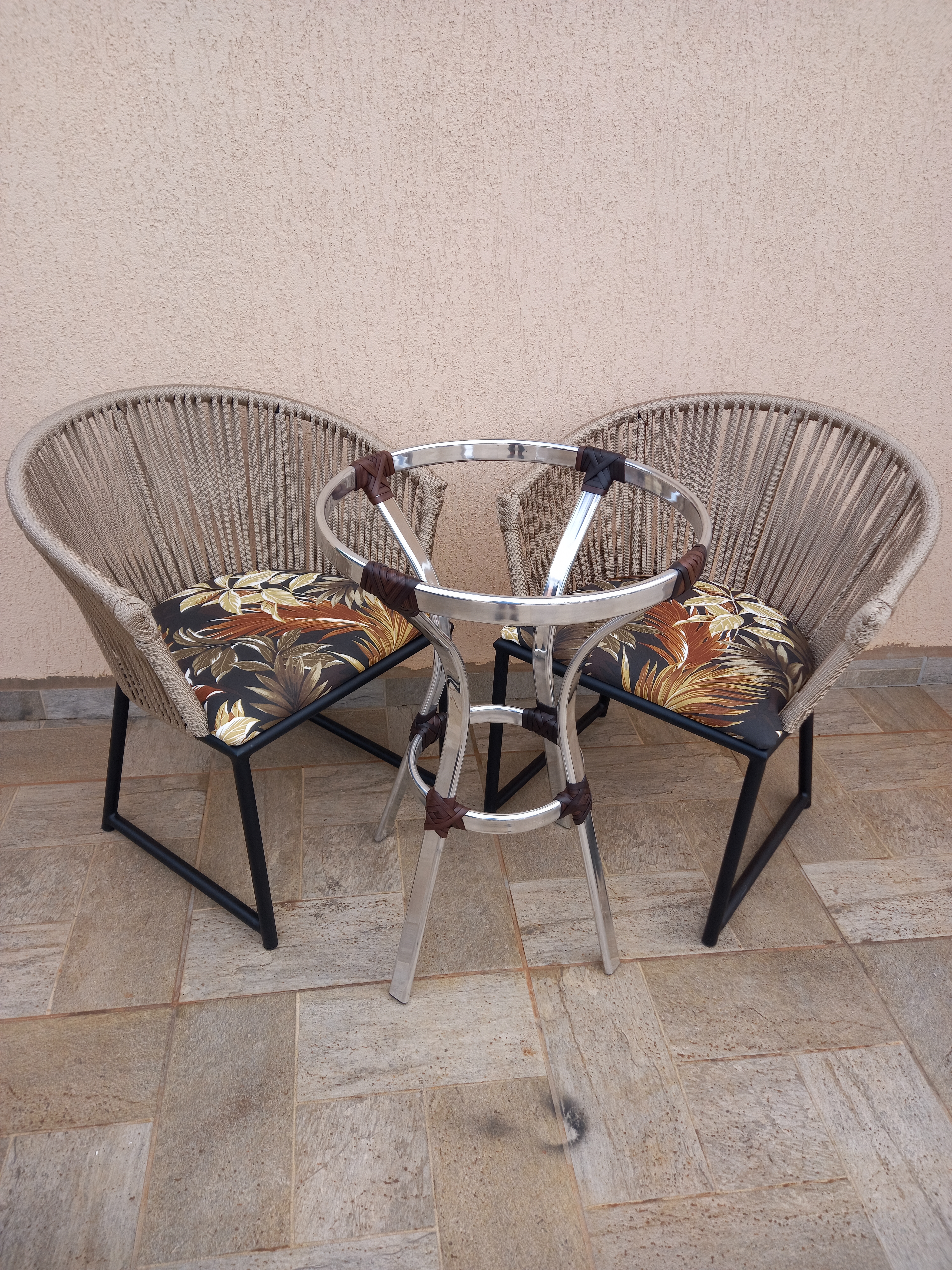 Área externa moderna com espreguiçadeira, vasos de plantas, parede de concreto e móveis de madeira sob luz natural.