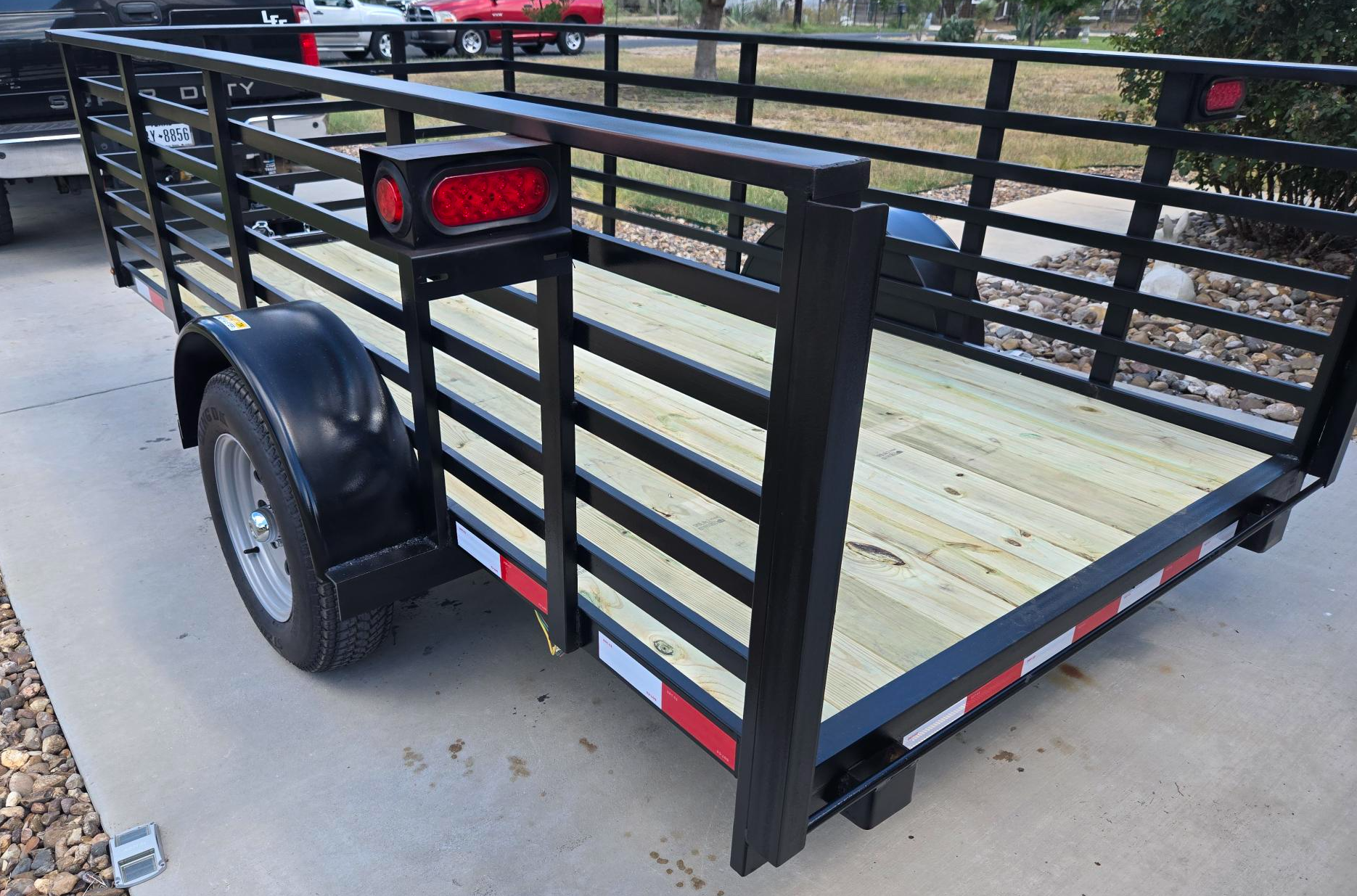 Blue enclosed cargo trailer with tandem axles and diamond plate trim in a warehouse setting.