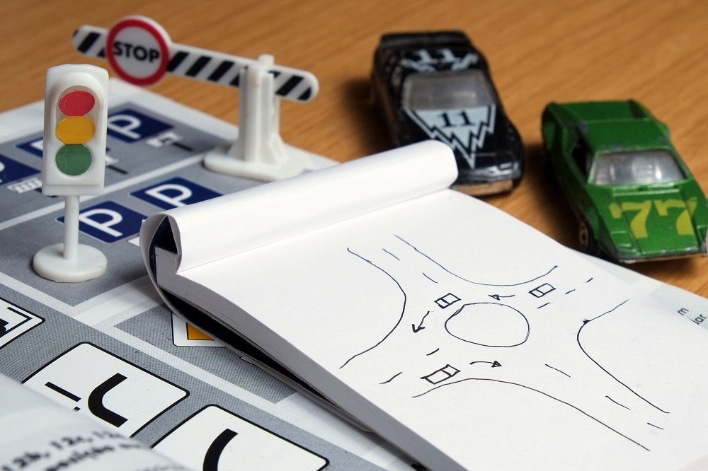 Toy cars and notebook with traffic pattern