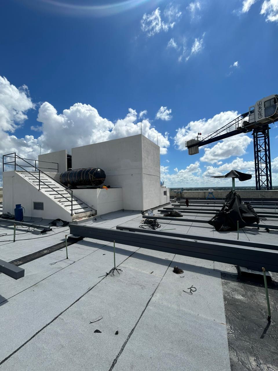Techo de edificio en construcción con cielo despejado y grúa visible.