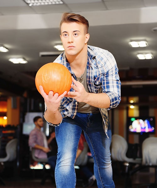 Young Man Playing Bowling In Club