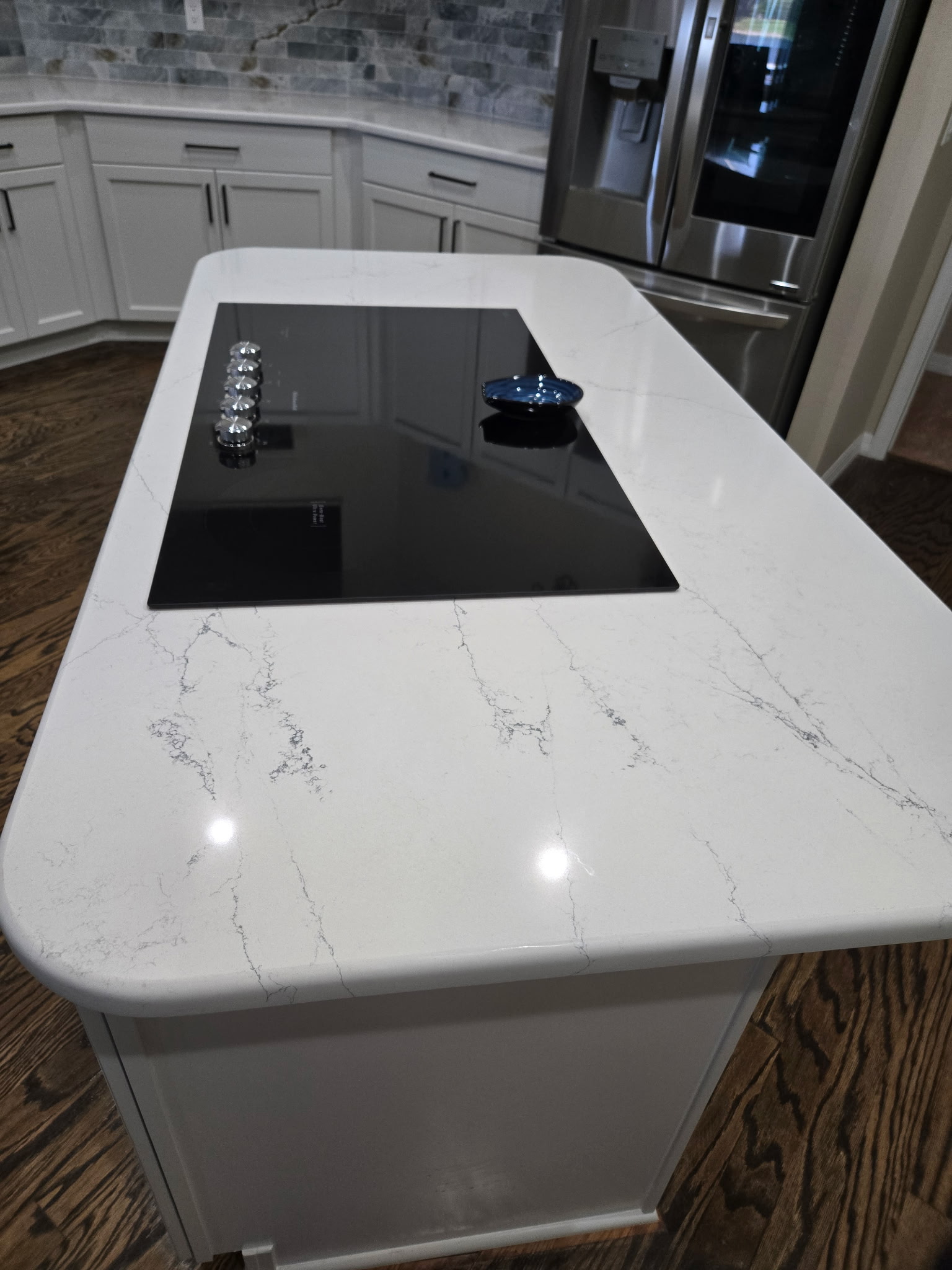 The island creates an ideal space for cooking, while the rounded quartz countertop adds a soft, inviting feel, enhancing comfort around the cooktop.