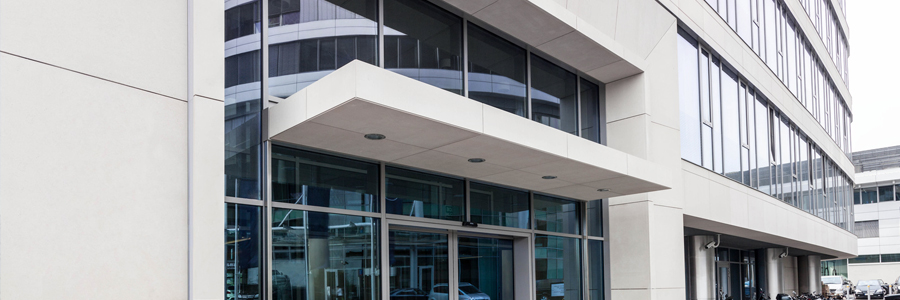 Modern office building facade with glass windows and entrance awning.