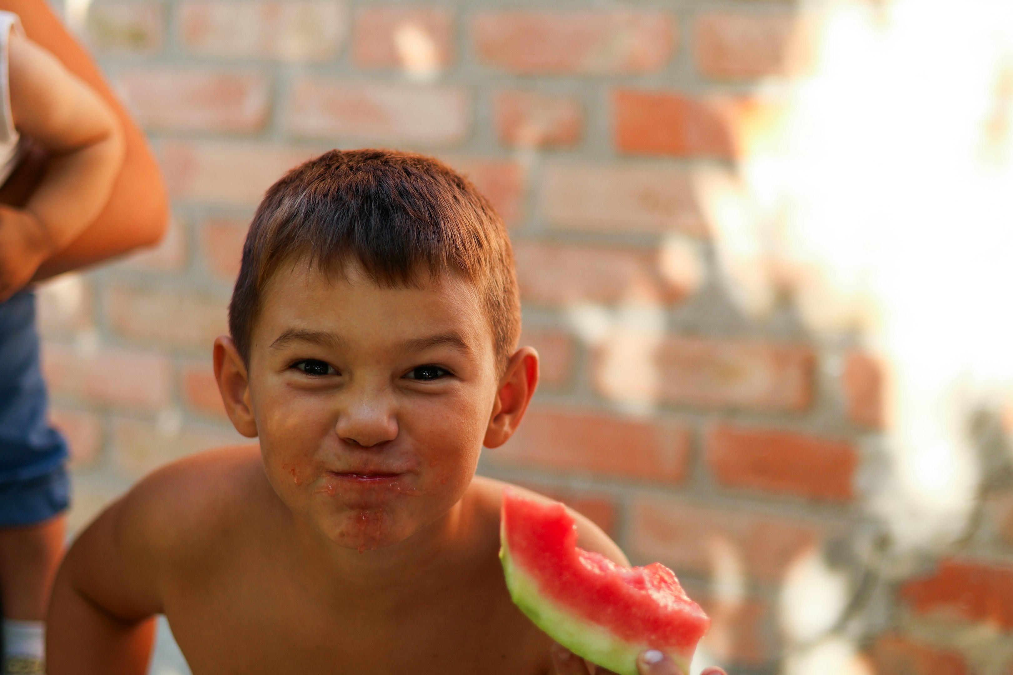 a young boy eating a piece of watermelon