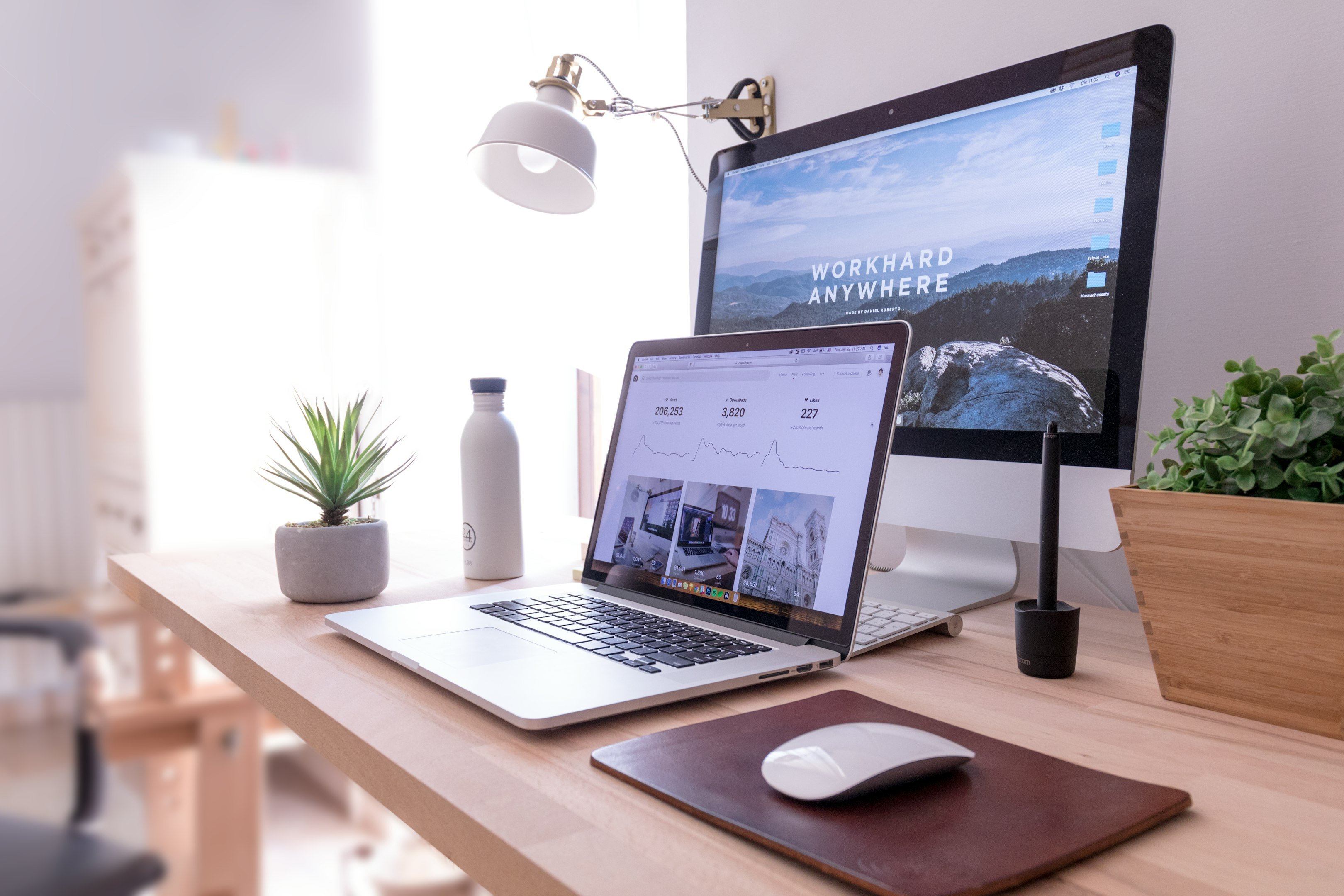 MacBook Pro en mesa al lado de iMac blanco y Magic Mouse