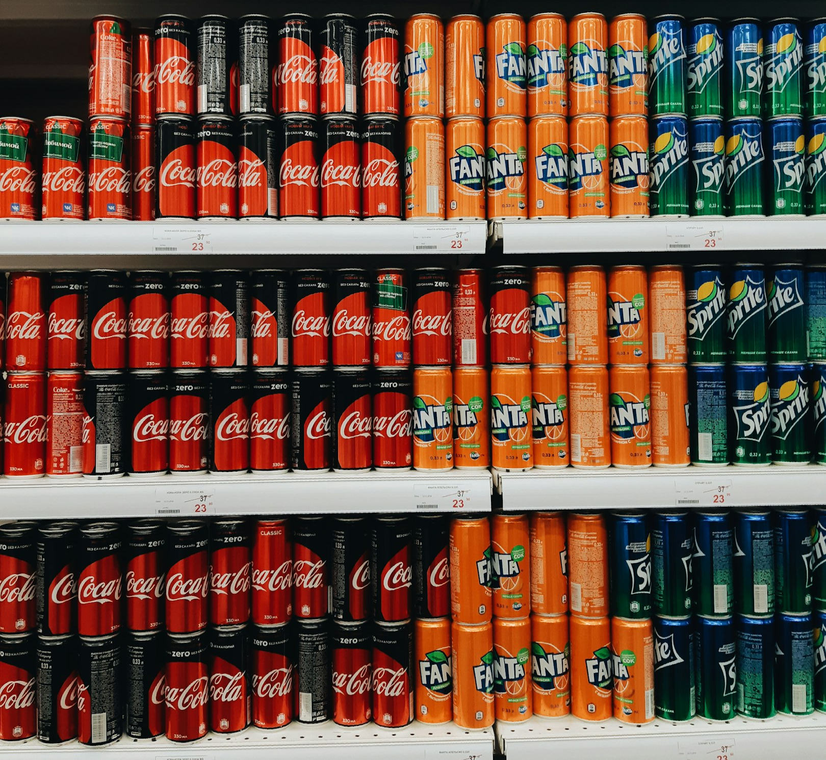 Pasillo de supermercado con estantes llenos de botellas y productos alimenticios variados.