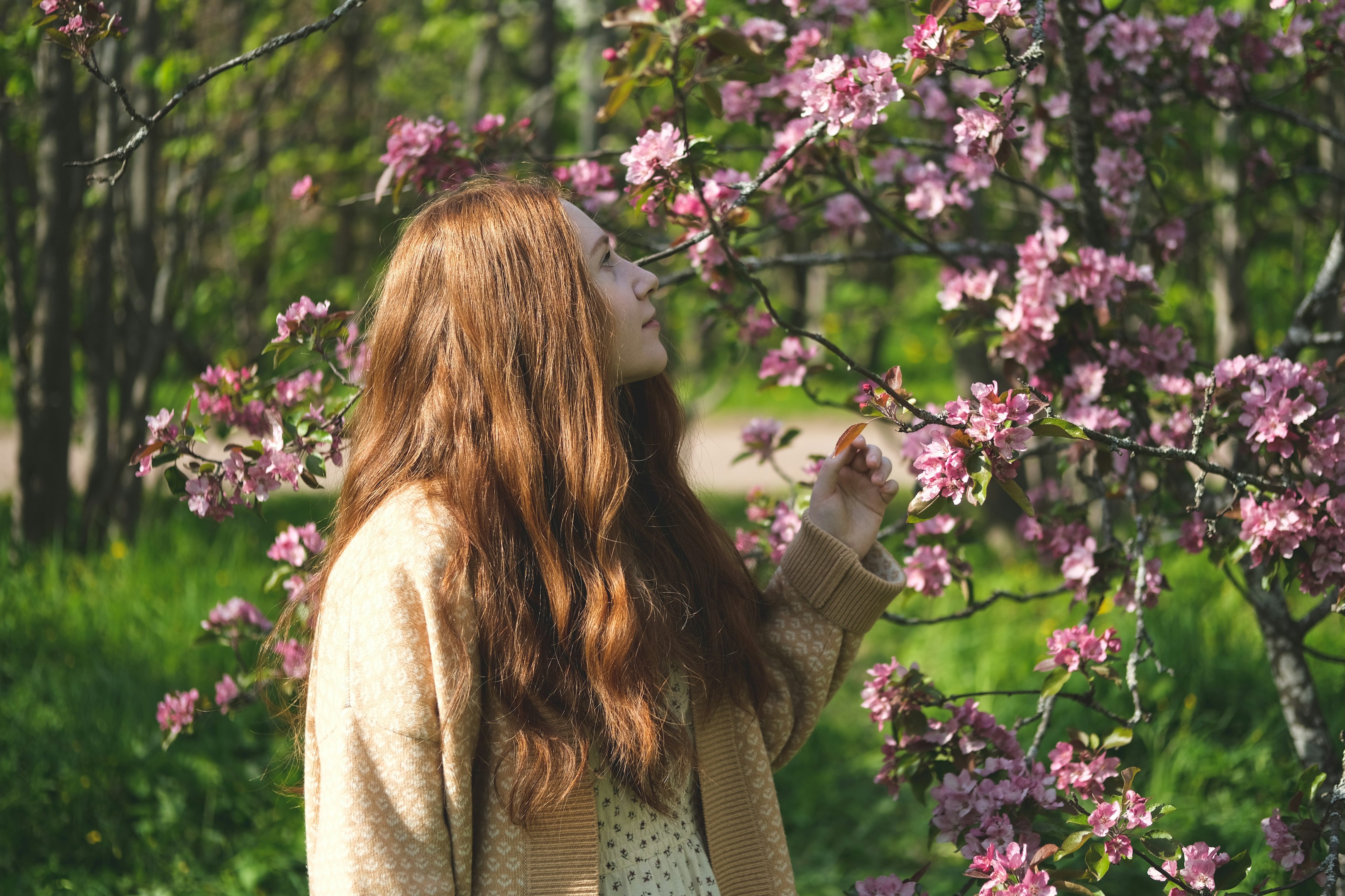 una mujer de pie frente a un árbol con flores rosas