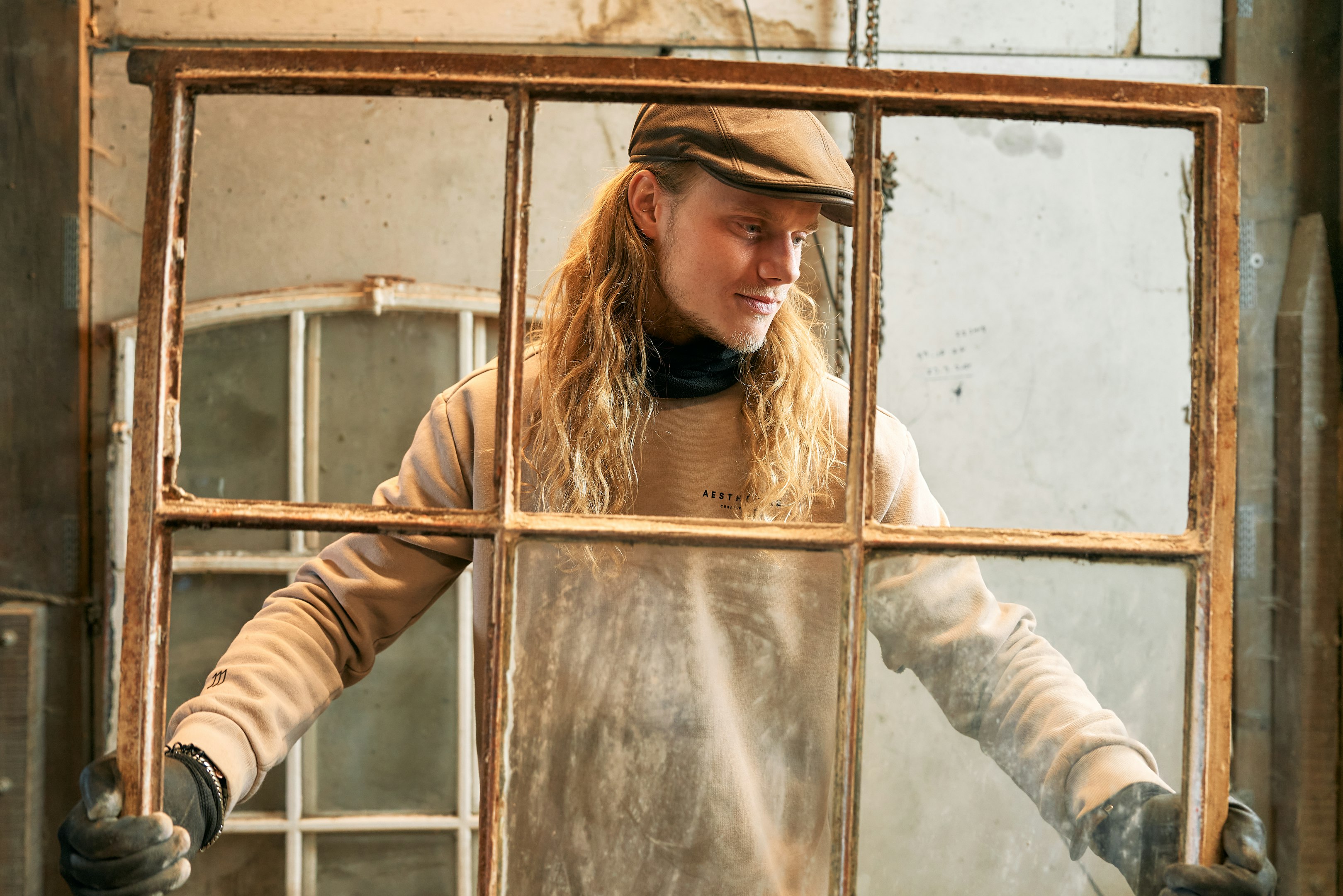 A woman wearing a hat and gloves standing in front of a window