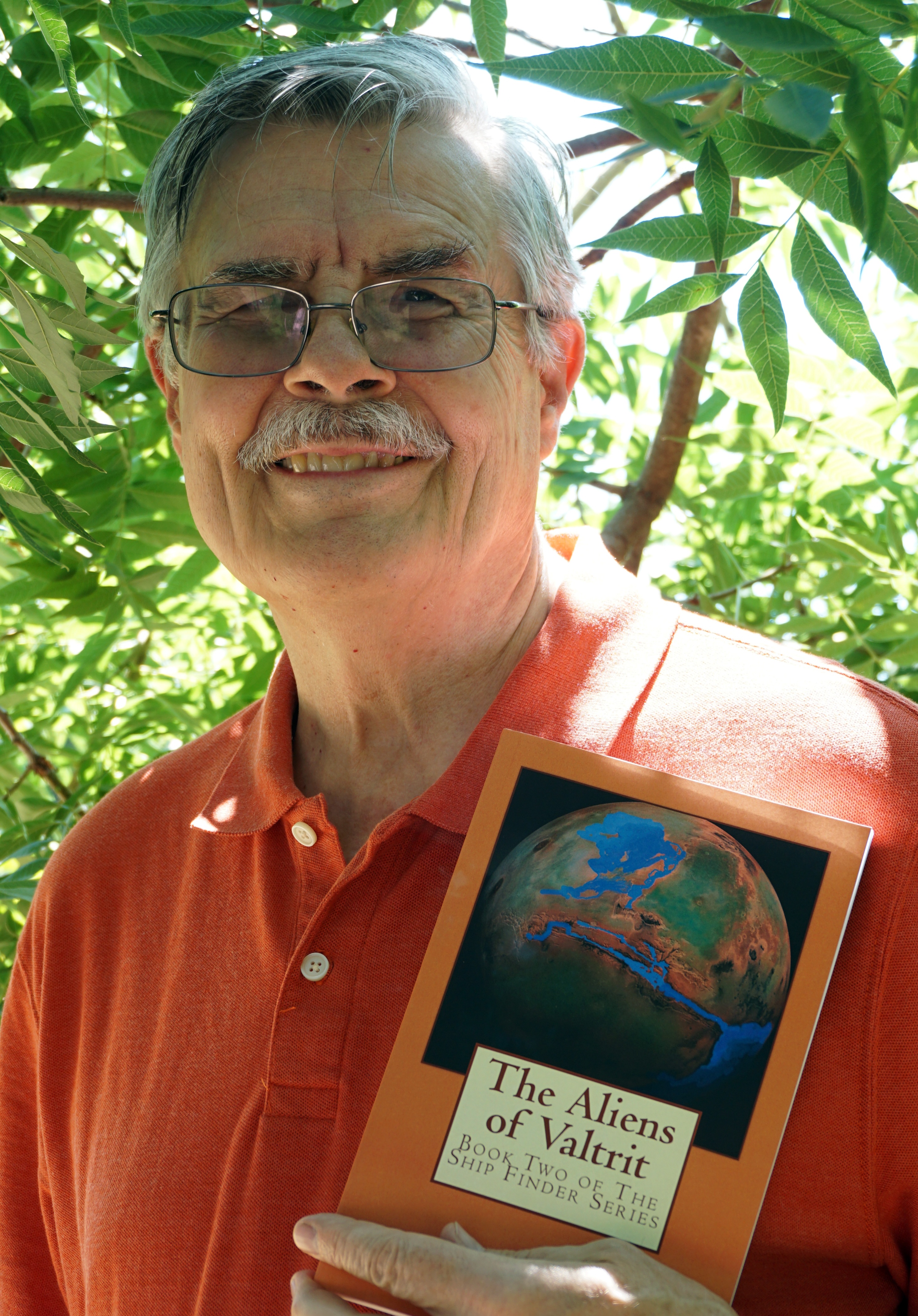 Author John G Bluck with a copy of his sci-fi novel, "The Aliens of Valtrit."