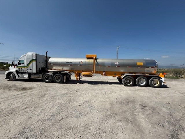 Camión azul de Transmate circulando por una autopista con movimiento y un cielo nublado. Camión azul de Transmate circulando por una autopista con movimiento y un cielo nublado.