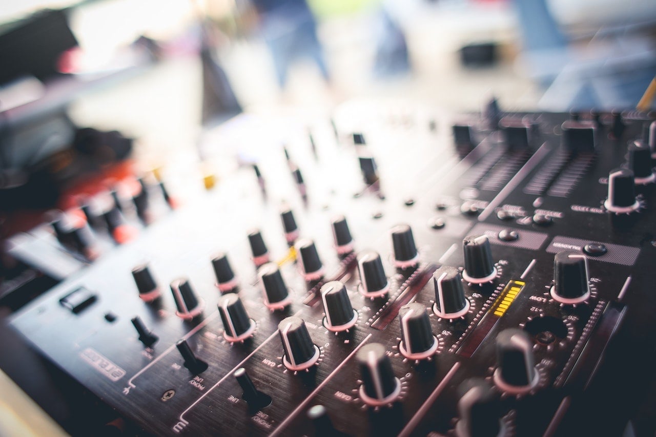 Close-up view of a professional audio mixing console with various control knobs and sliders.