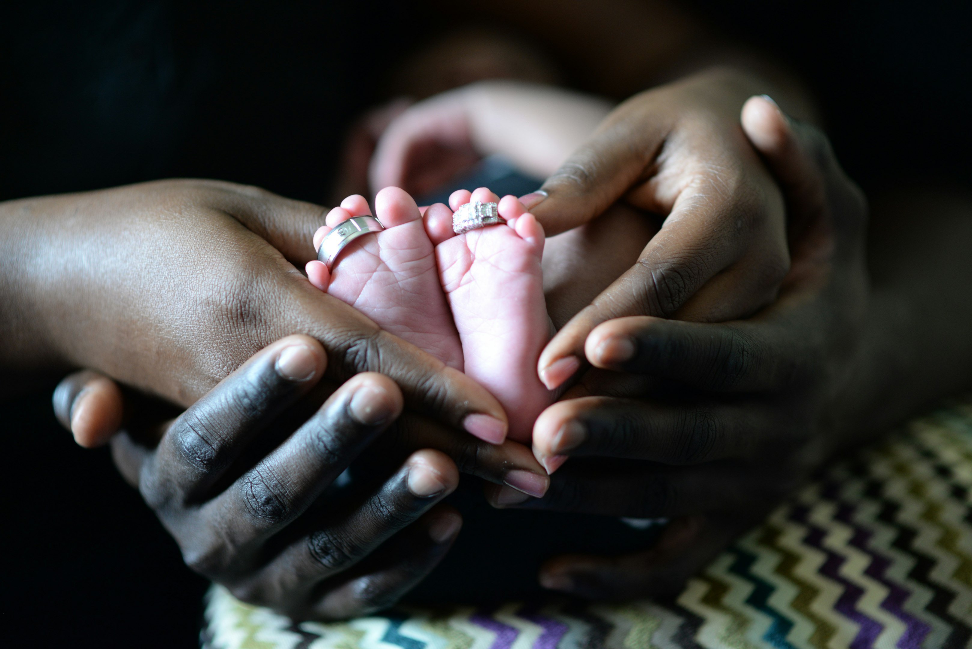 persona tocando los pies del bebé con dos anillos de plata