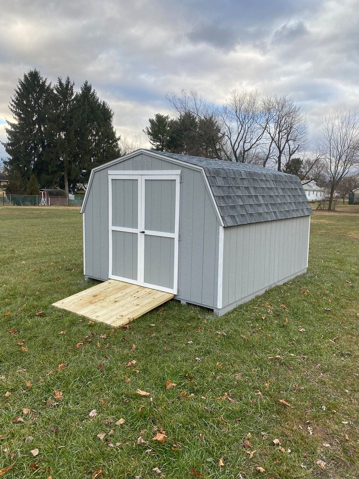 10 x 12 Budget Barn                   
                                                              
Featuring light gray colored wood siding, white trim, and charcoal gray colored 30 year architectural shingles (with tarpaper underlayment), gable vents, pressure treated floor joists, and a 24”x27” slider window with a screen, all my structures come with a 10 year warranty of materials and workmanship.

Shown with optional treated ramp.