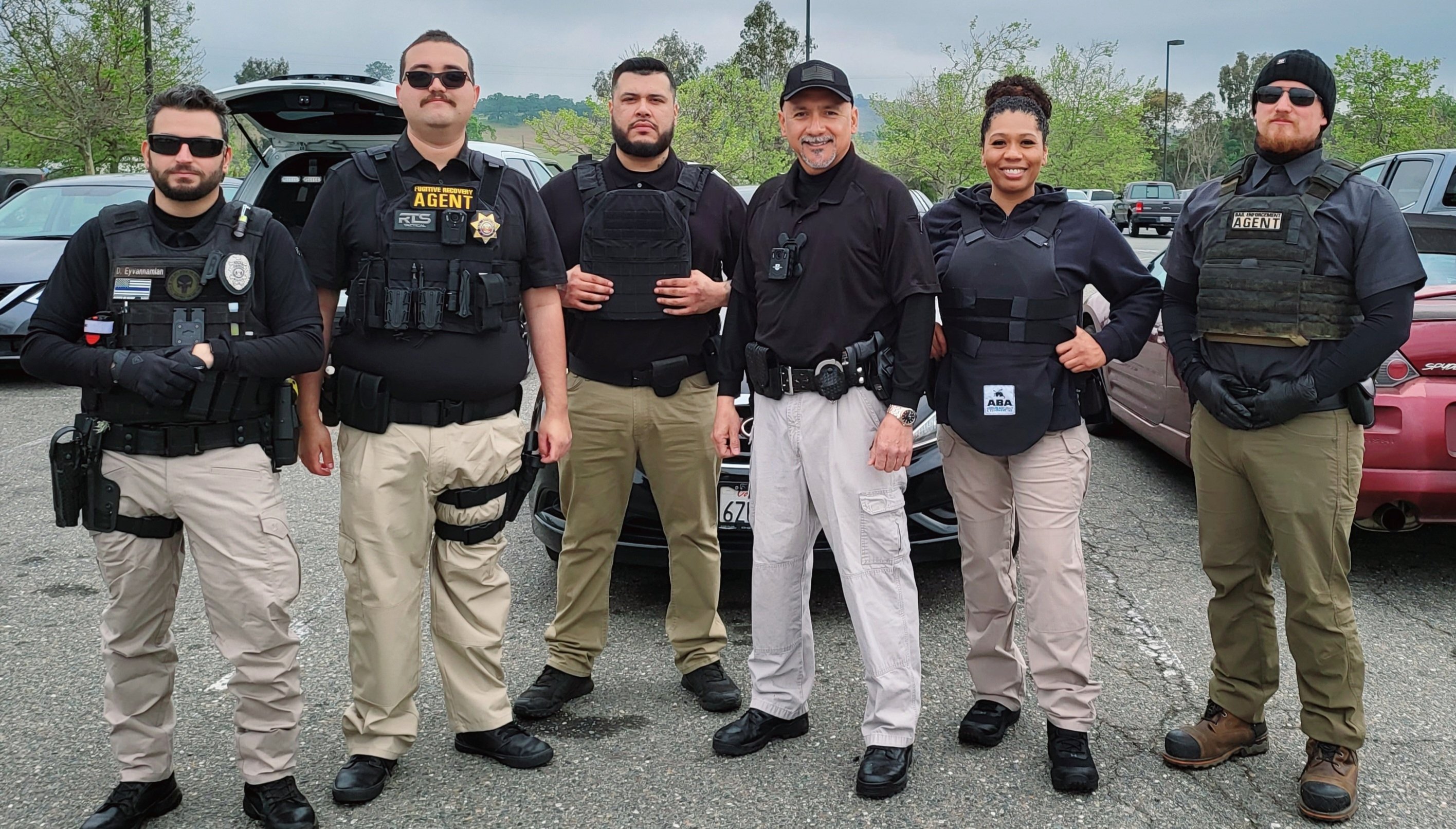 Group of tactical team members in uniform standing together outdoors.