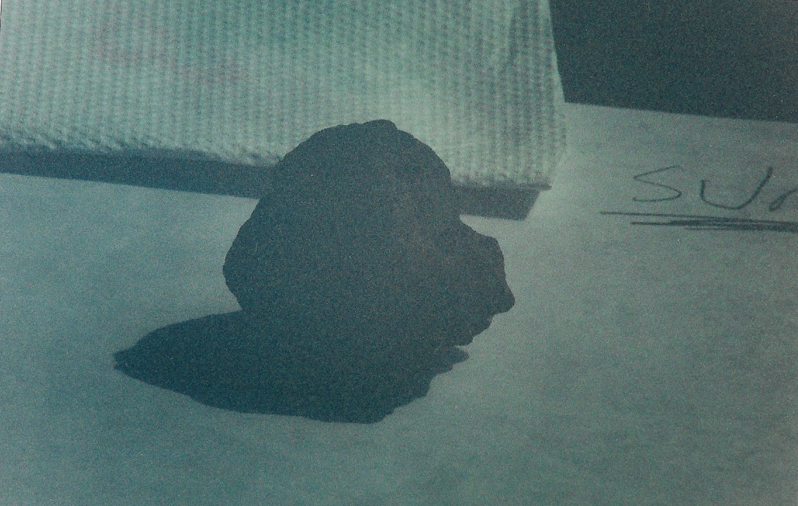 The gemstone and shadow are the same shade of black. The surface of the gemstone is void of any visual detail. There is a faint reddish color glow centered around the gemstone along with other subtle colors. All of the colors in this image as well as the room blackout effect cannot be seen with the naked eye. This room is sun light bright. This photo was taken with a Minolta maxium 7000 AF with a telescopic lens maxxum 2000 AF 70-210 1:4(32)mm. The gemstone and shadow are the same shade of black. The surface of the gemstone is void of any visual detail. There is a faint reddish color glow centered around the gemstone along with other subtle colors. All of the colors in this image as well as the room blackout effect cannot be seen with the naked eye. This room is sun light bright. This photo was taken with a Minolta maxium 7000 AF with a telescopic lens maxxum 2000 AF 70-210 1:4(32)mm.