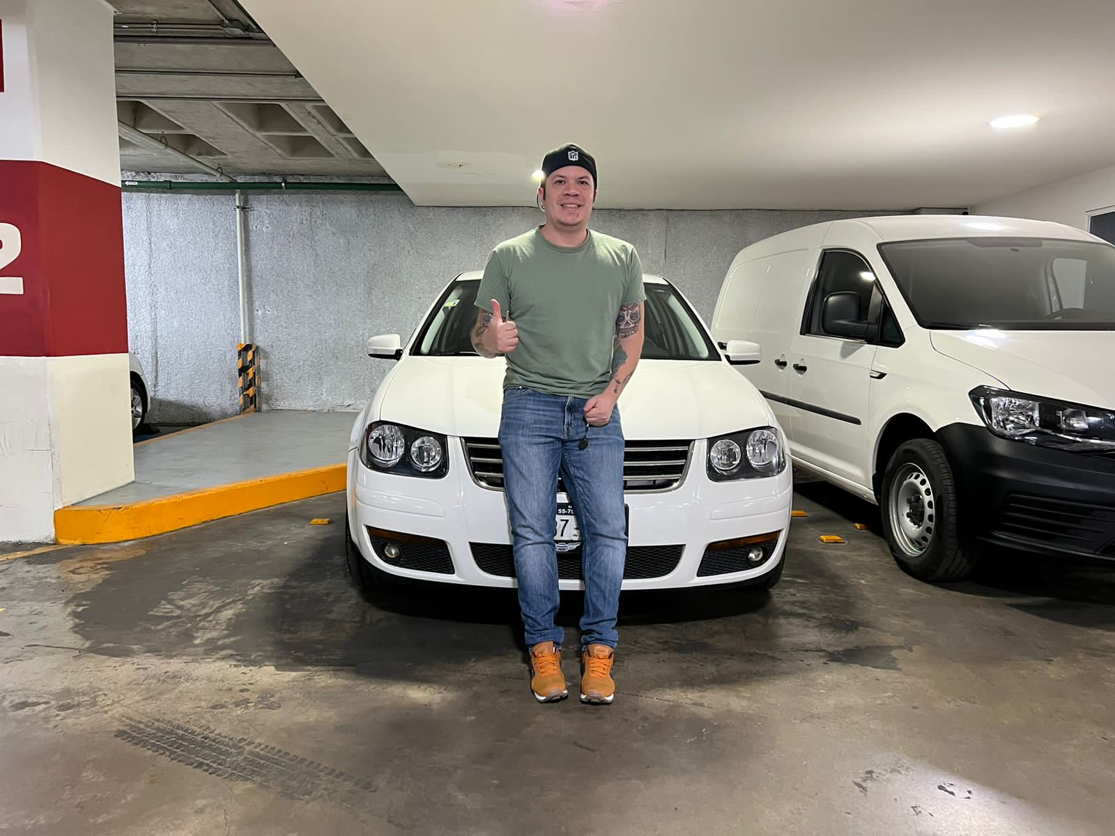 Man standing beside white Toyota truck in underground parking garage with adjacent parked vehicles.