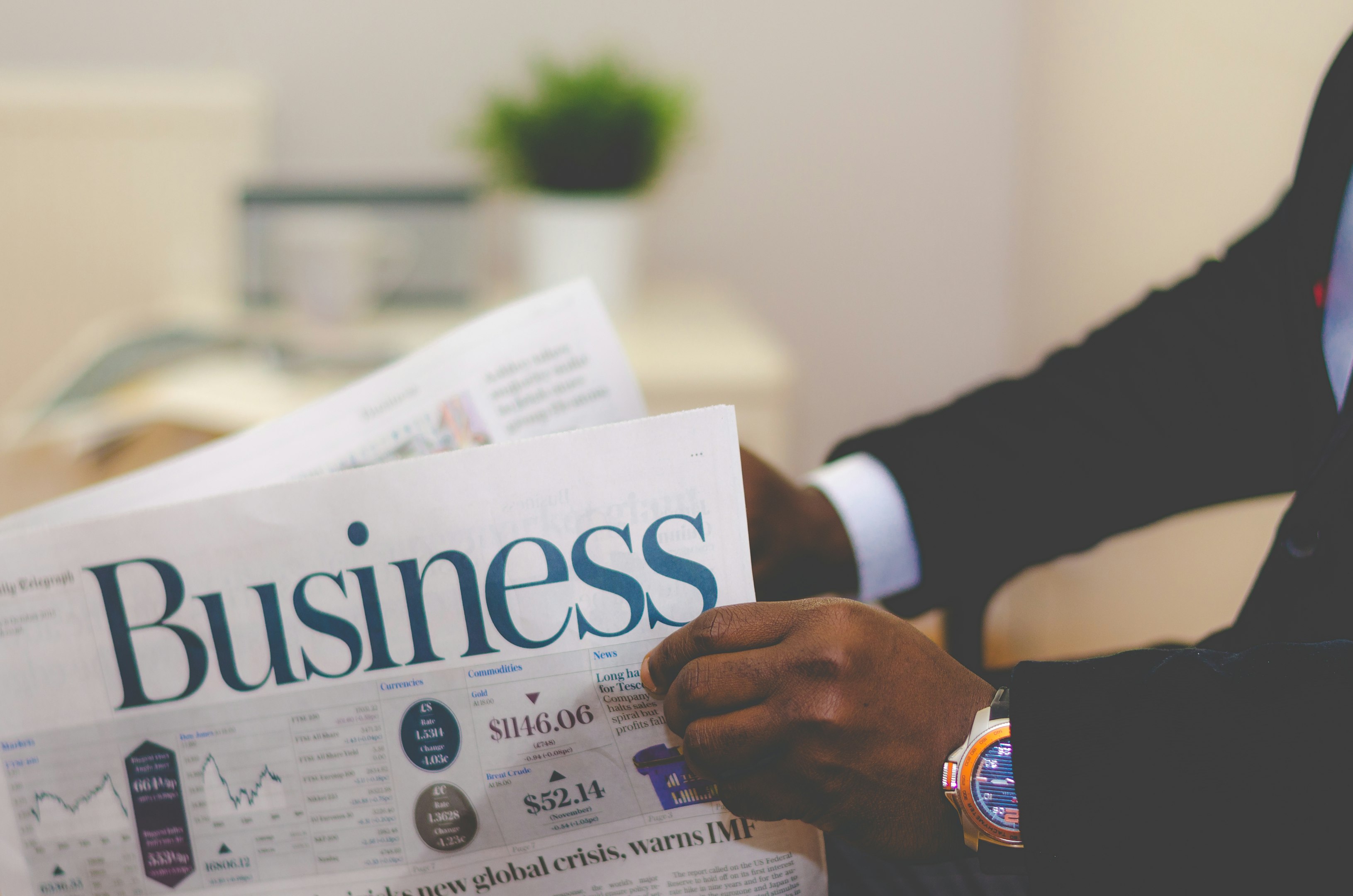 persona con traje leyendo periódico de negocios