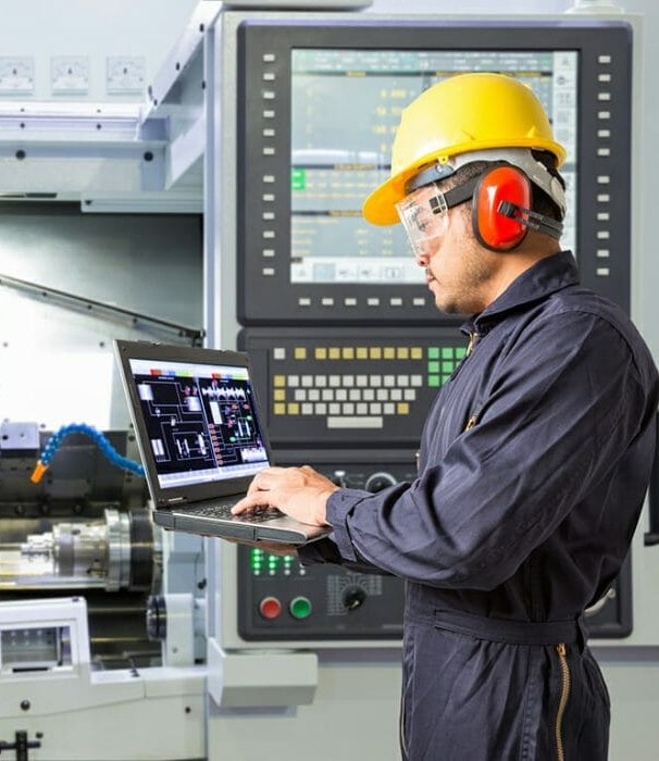 Máquina CNC ARDTEC en una moderna fábrica iluminada con grandes luces LED, rodeada de mesas de trabajo y sillas.