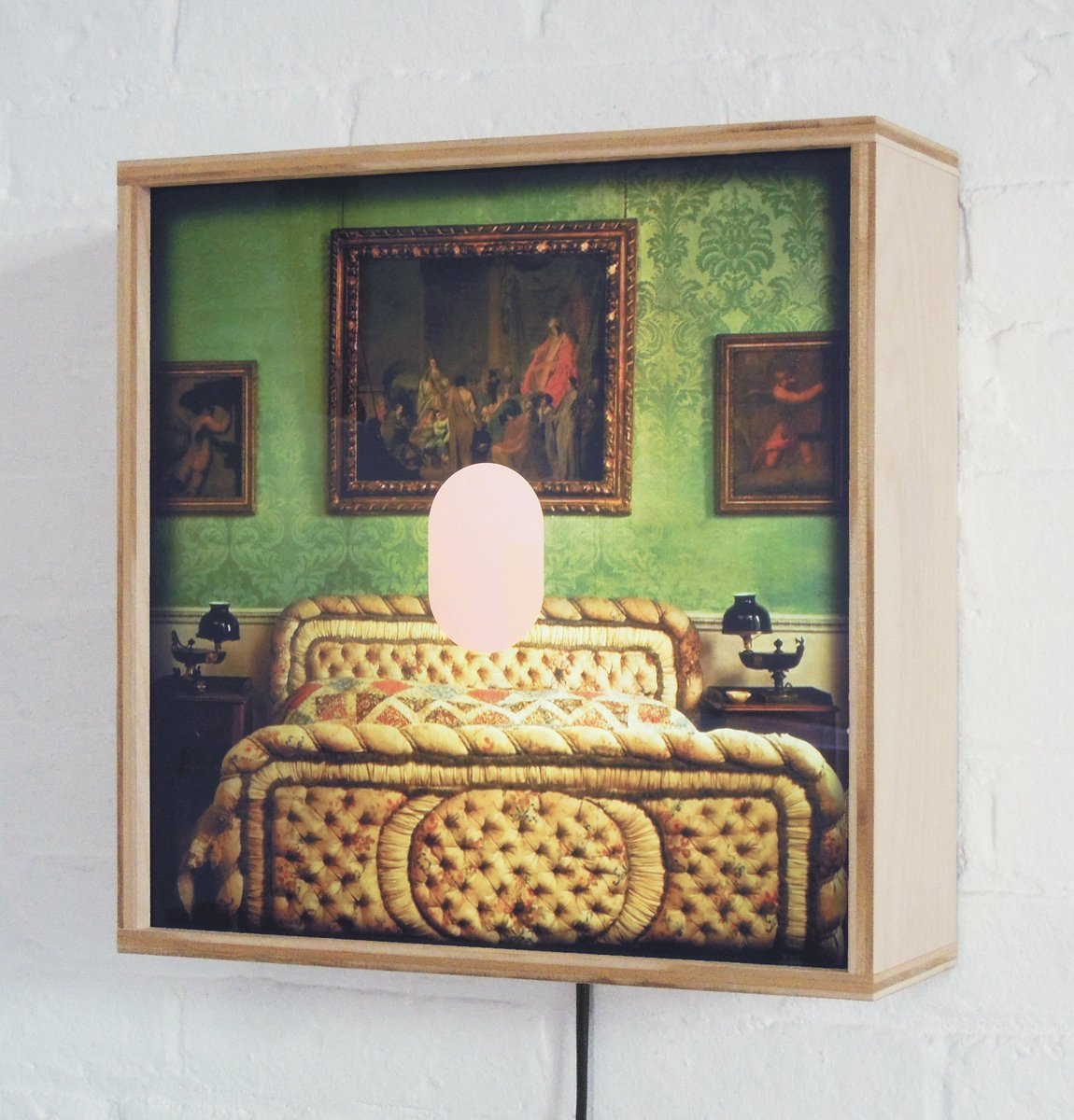 A plywood lightbox contains an image of an opulent bedroom and a pink oval.