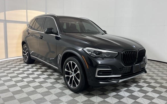 Red sports car with black racing stripes in a modern showroom.