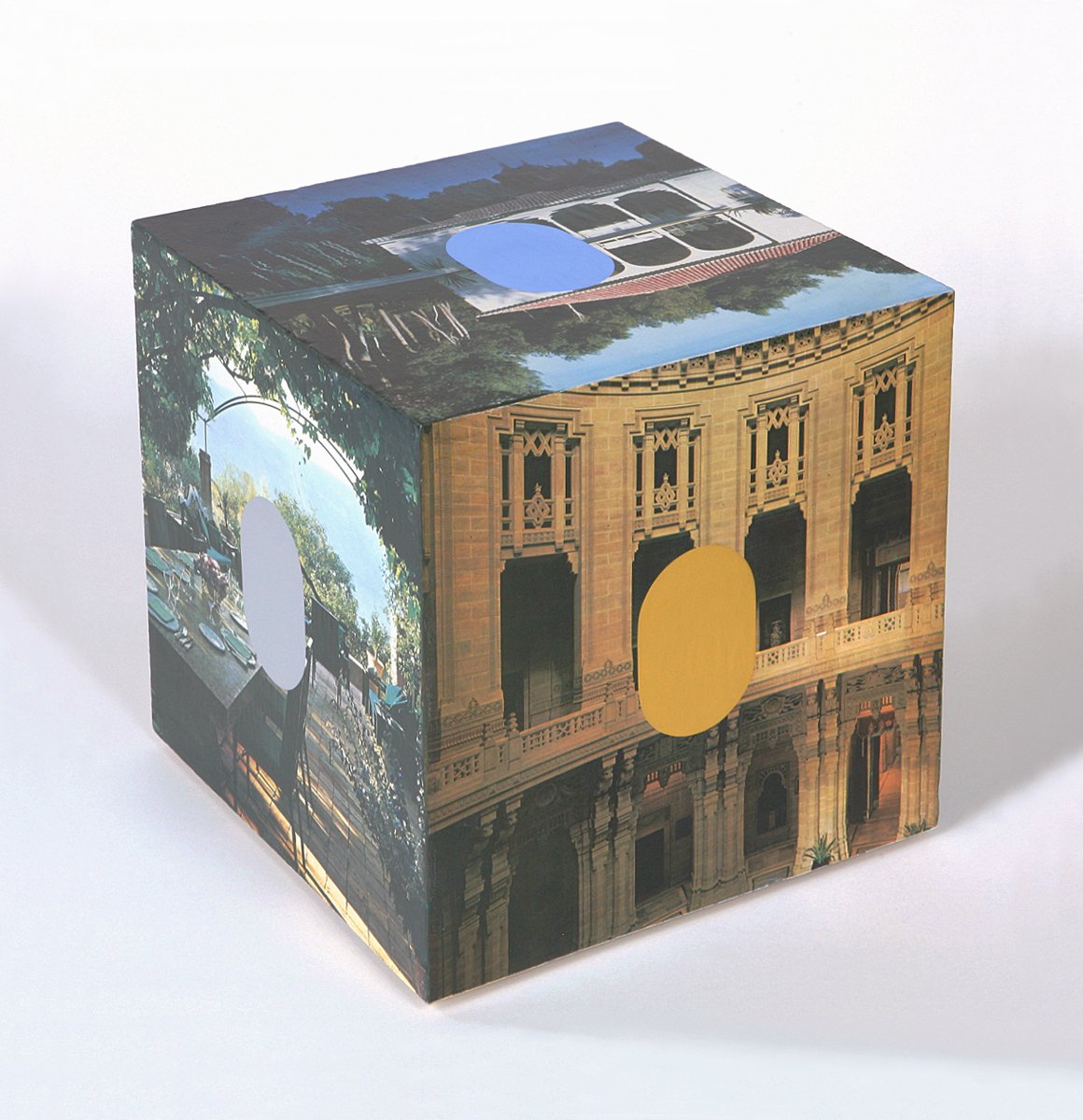 A cube with architectural images and blue, grey and ochre ovals on the outside.