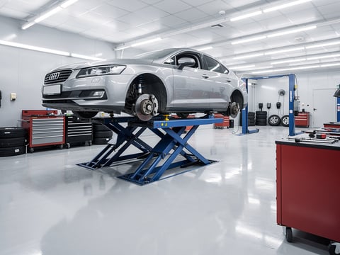 Audi plateado elevado en taller mecánico moderno para reparación y mantenimiento de automóviles