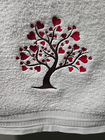 White hand towel with a heart tree design embroidered on it