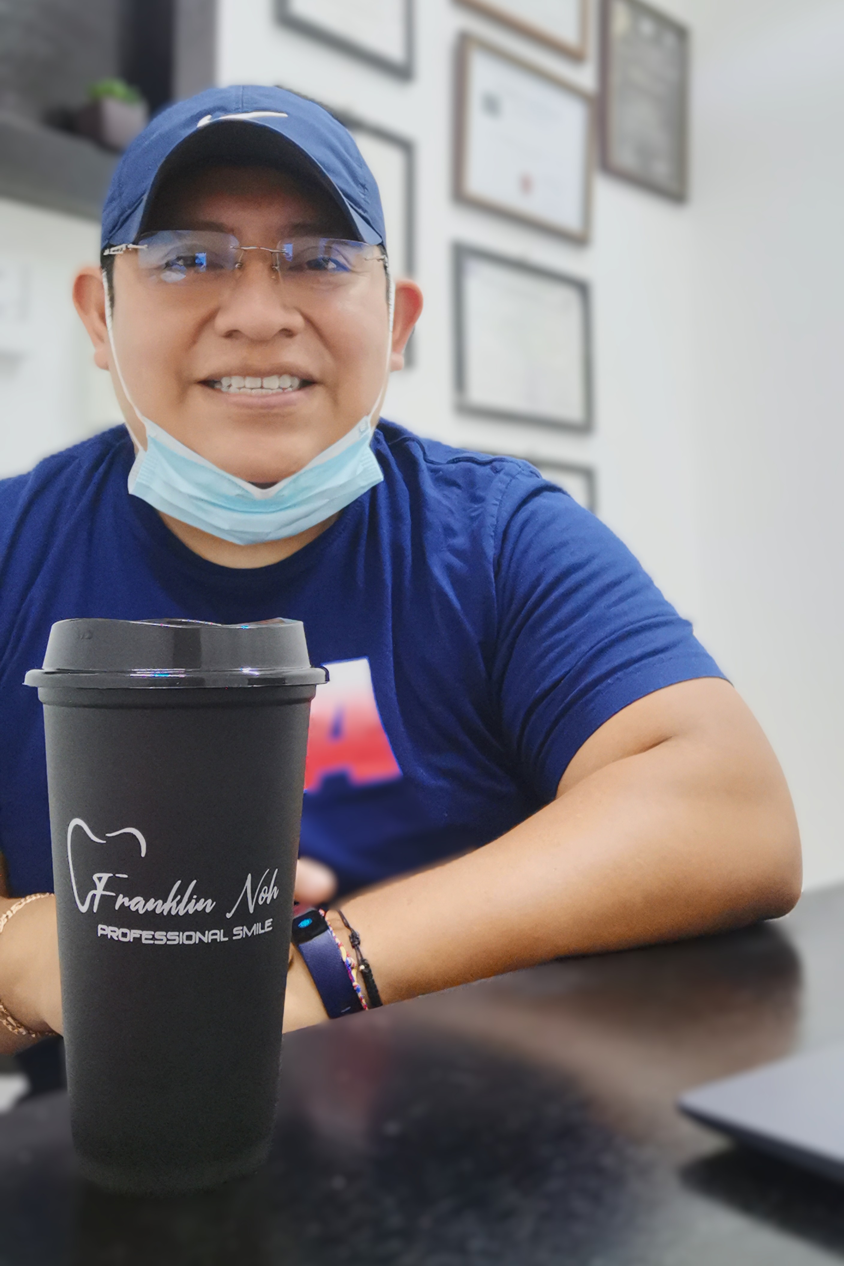 Hombre sonriendo con gorro colorido y bata blanca en ambiente clínico.