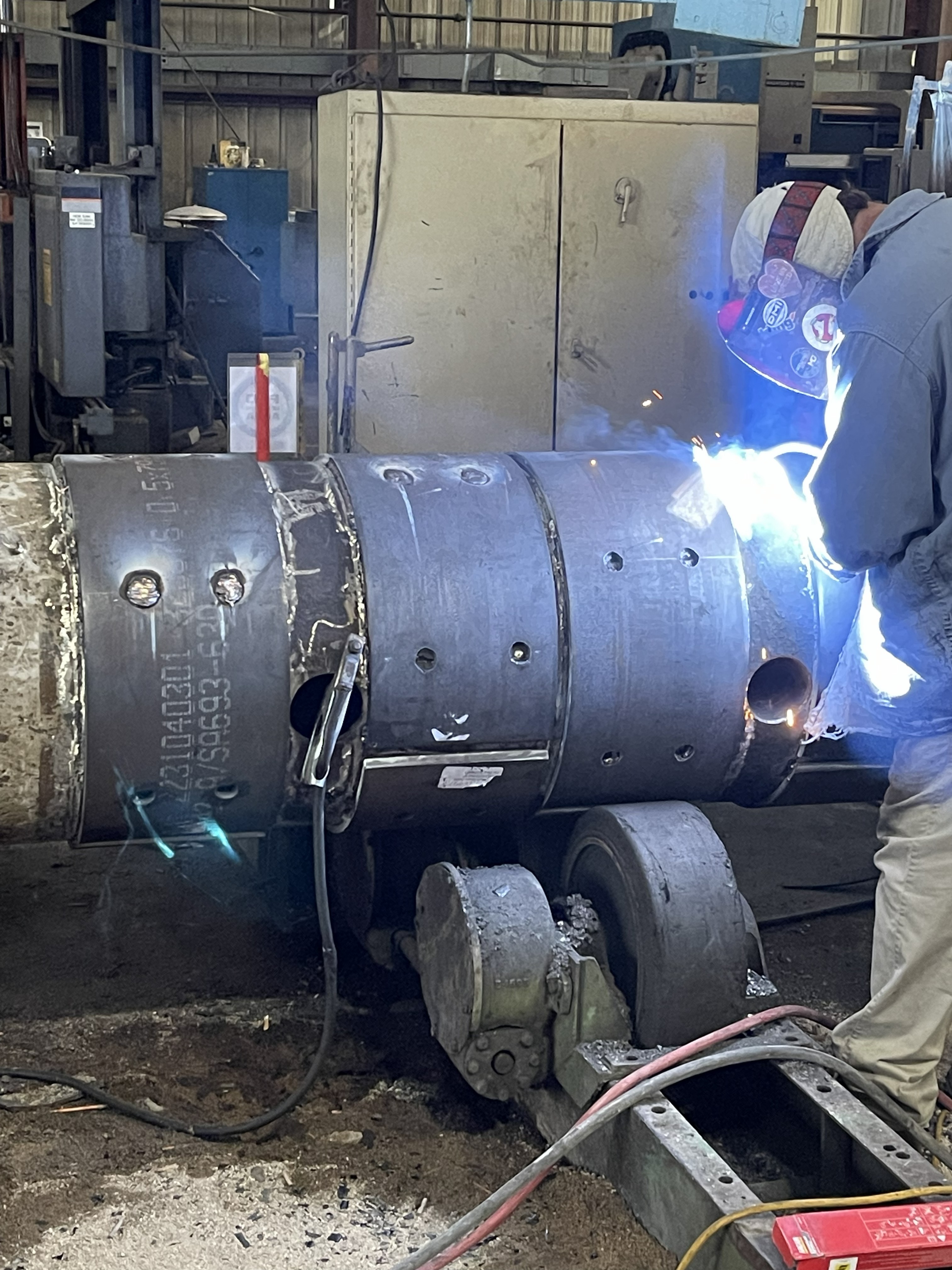 Modern industrial workshop with metal components on tables and advanced machinery in the background.