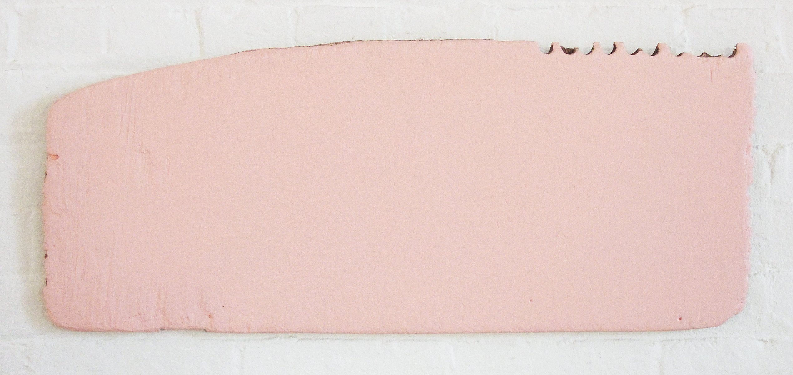 An irregularly shaped piece of plywood completely covered in pink paint.