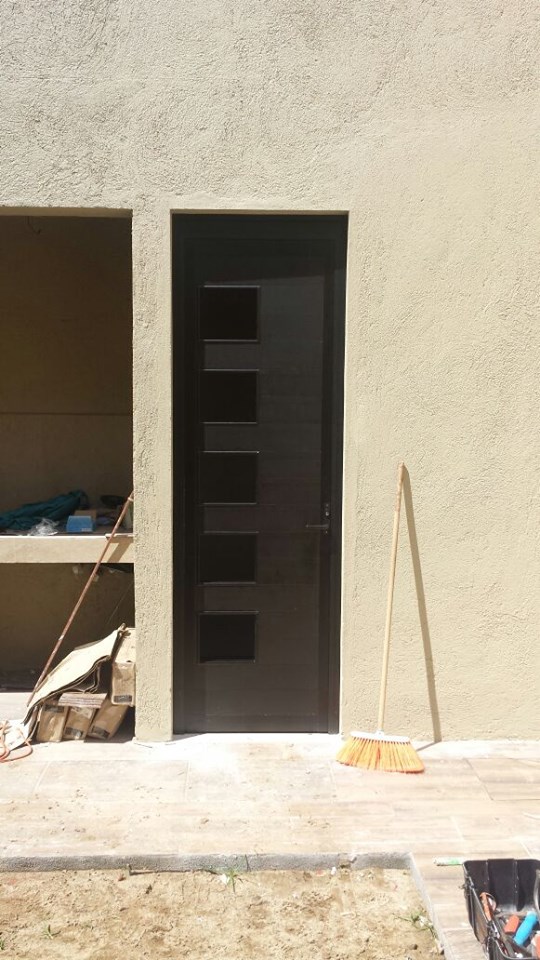 Puerta de aluminio en tono bronce con detalle a los lados para vidrio.