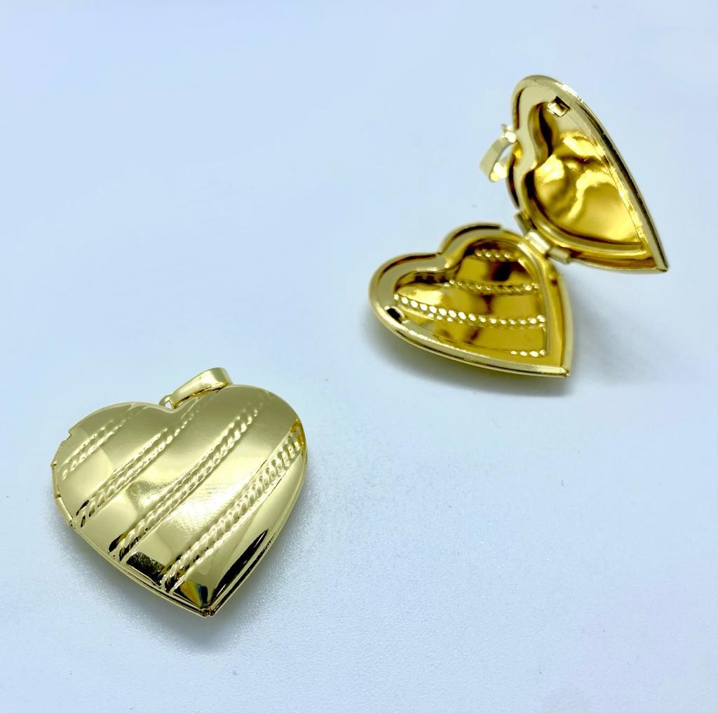 Colgantes dorados en forma de corazón, uno abierto y otro cerrado, sobre fondo blanco. Colgantes dorados en forma de corazón, uno abierto y otro cerrado, sobre fondo blanco.