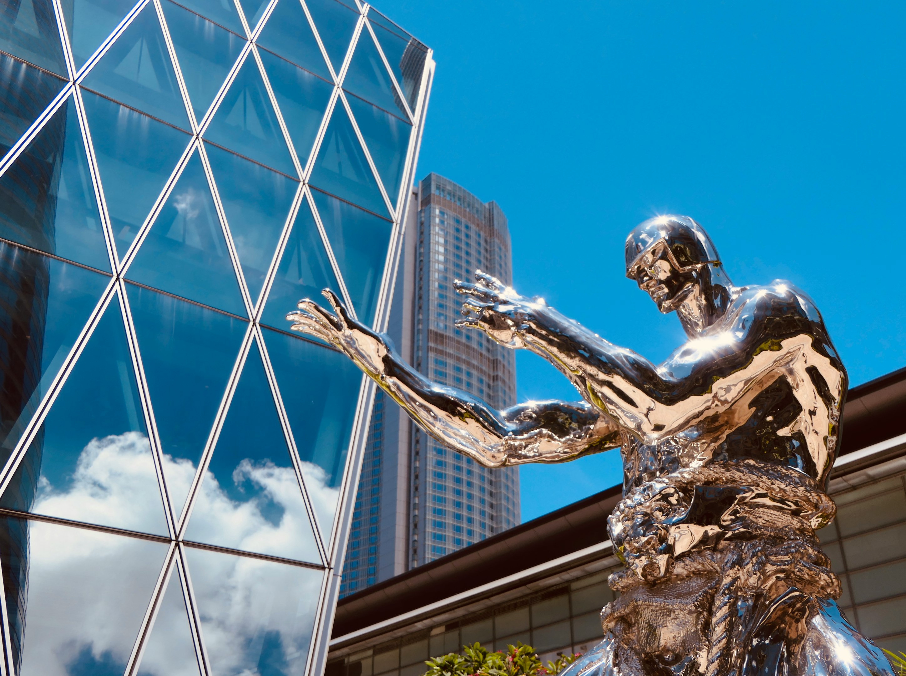man with wings statue near glass building during daytime