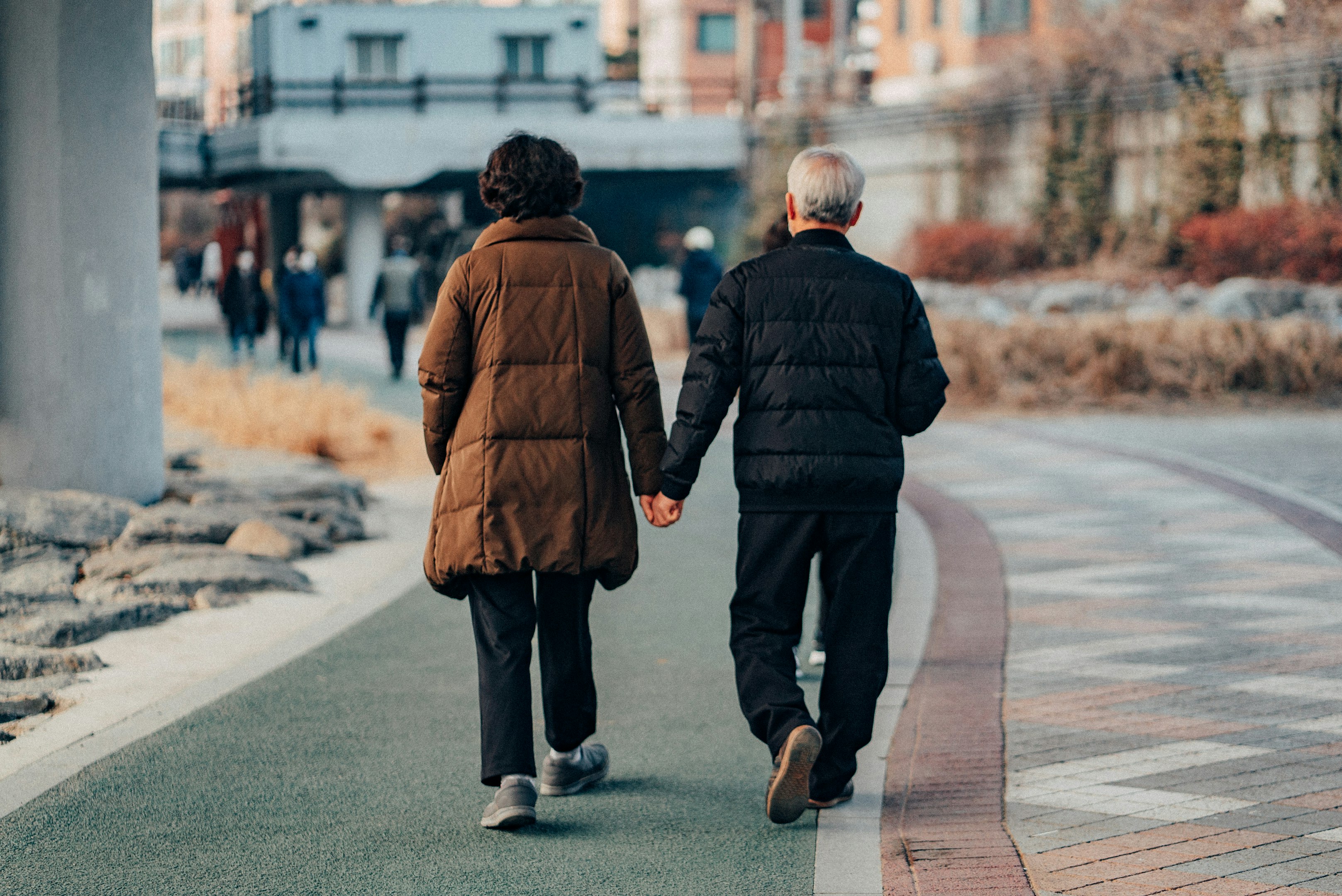man in brown jacket and gray pants walking on sidewalk during daytime man in brown jacket and gray pants walking on sidewalk during daytime