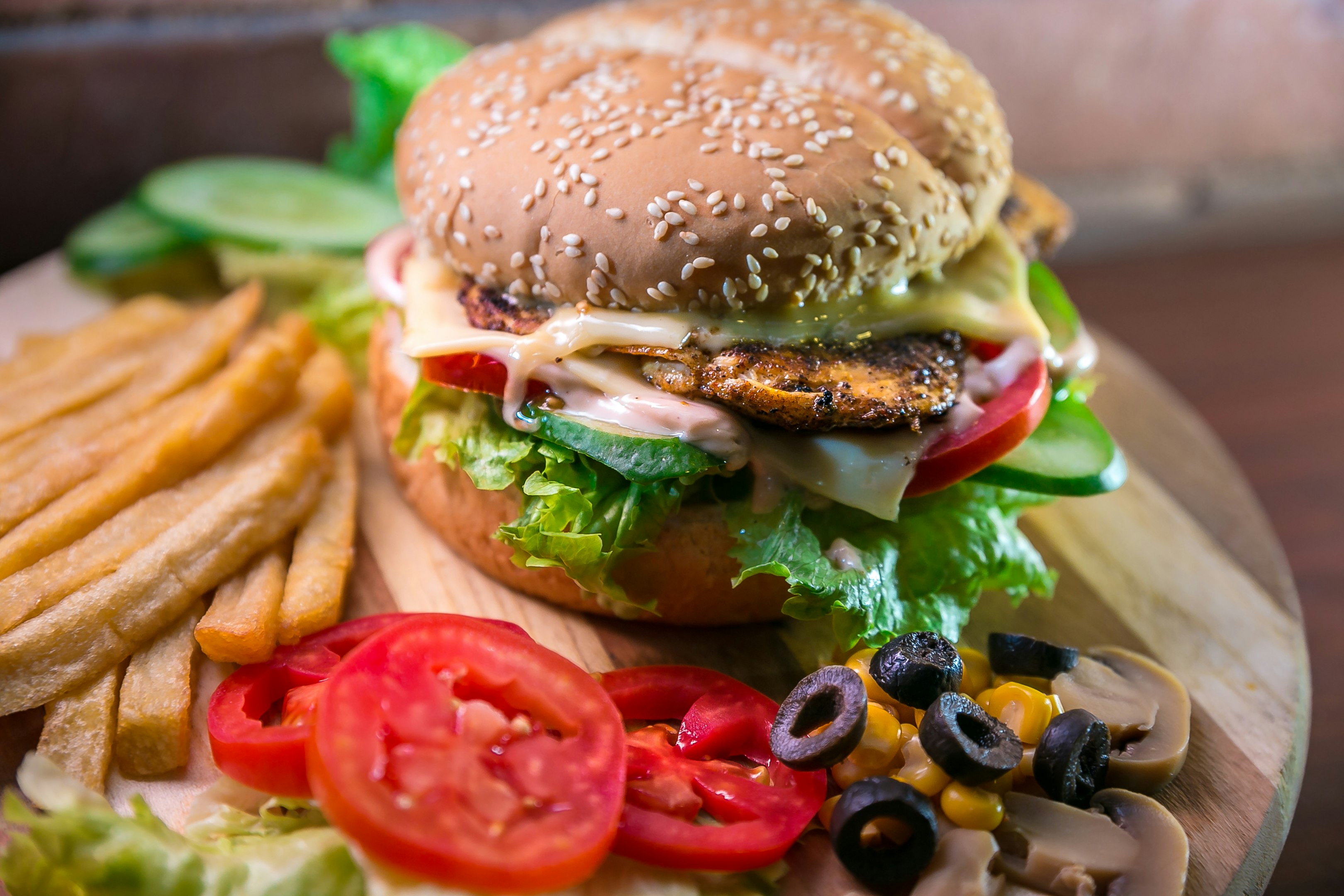hamburguesa con vegetales y carne junto a papas fritas