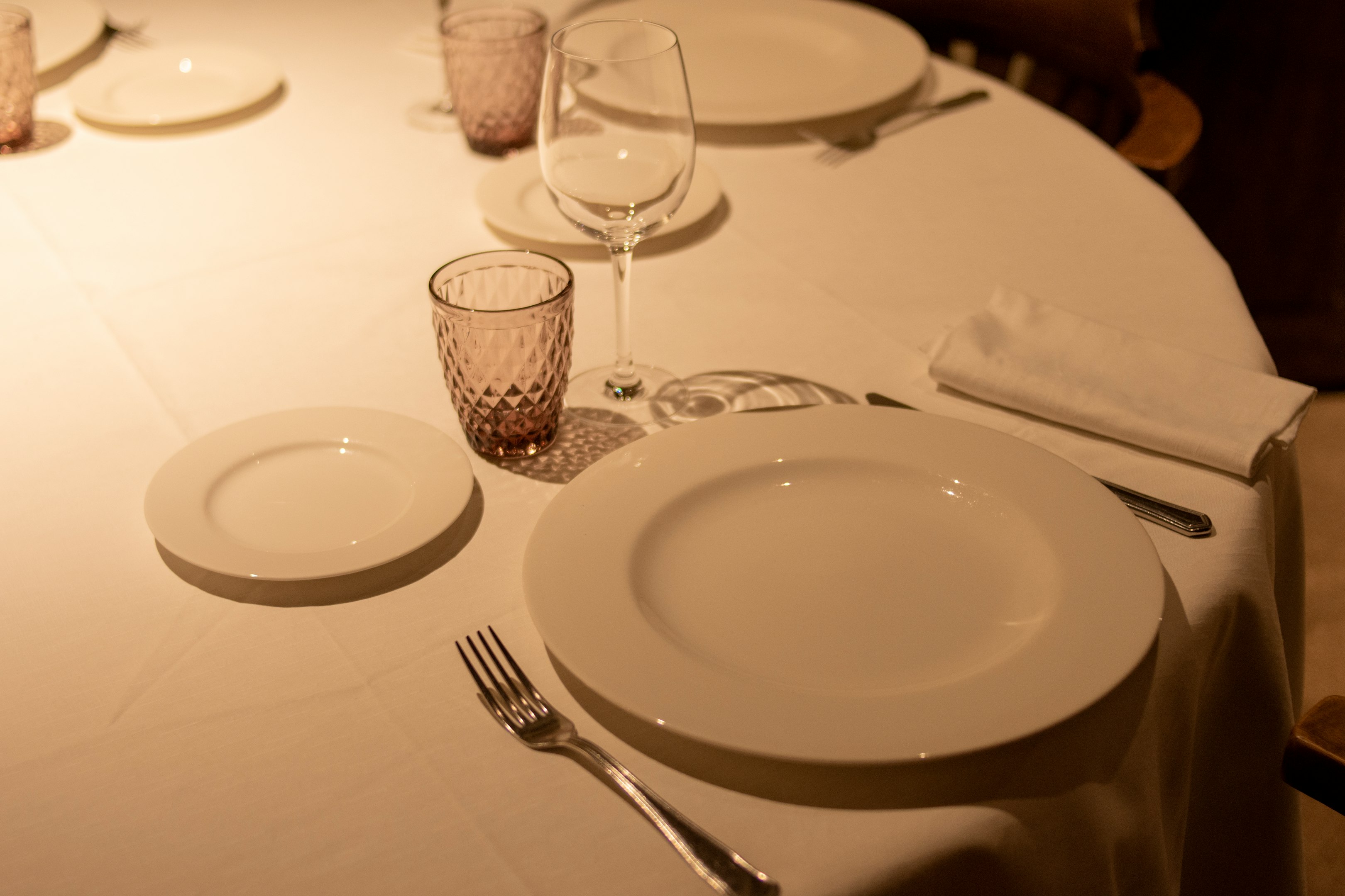 una mesa con un mantel blanco y lugares puestos