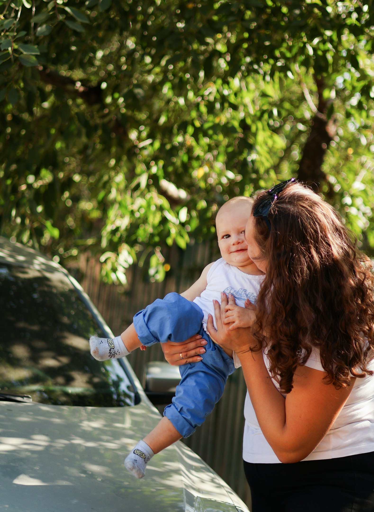 a woman holding a baby in front of a car