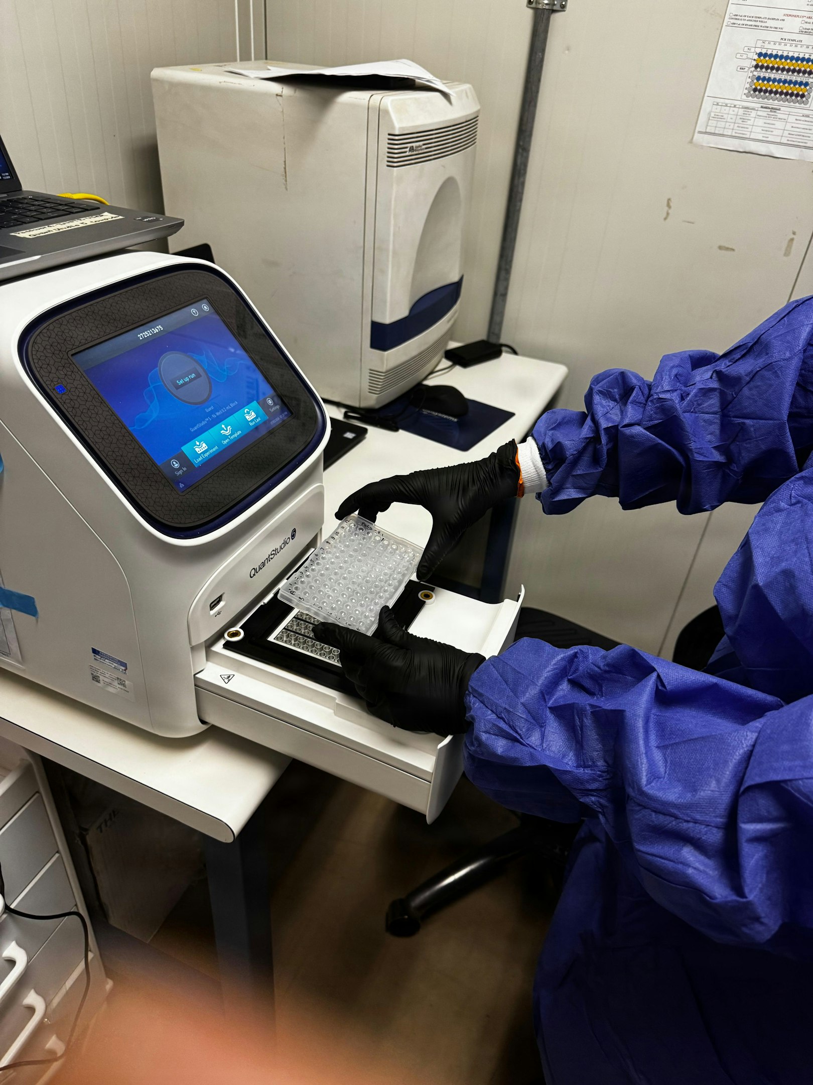 Person in ppe loads sample into laboratory testing machine
