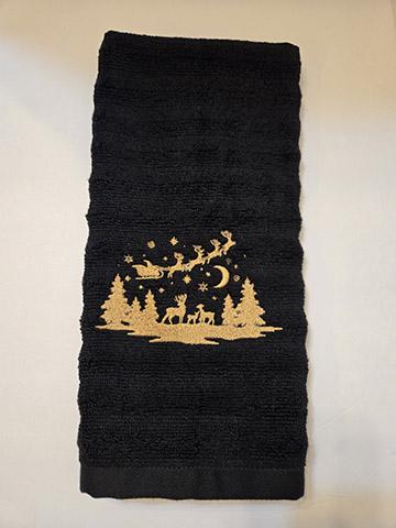 Black hand towel featuring Santa flying over the woods design