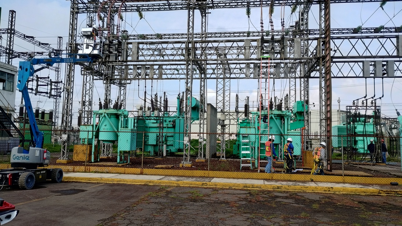 Ingenieros con cascos y chalecos de seguridad operando panel de control en fábrica industrial moderna