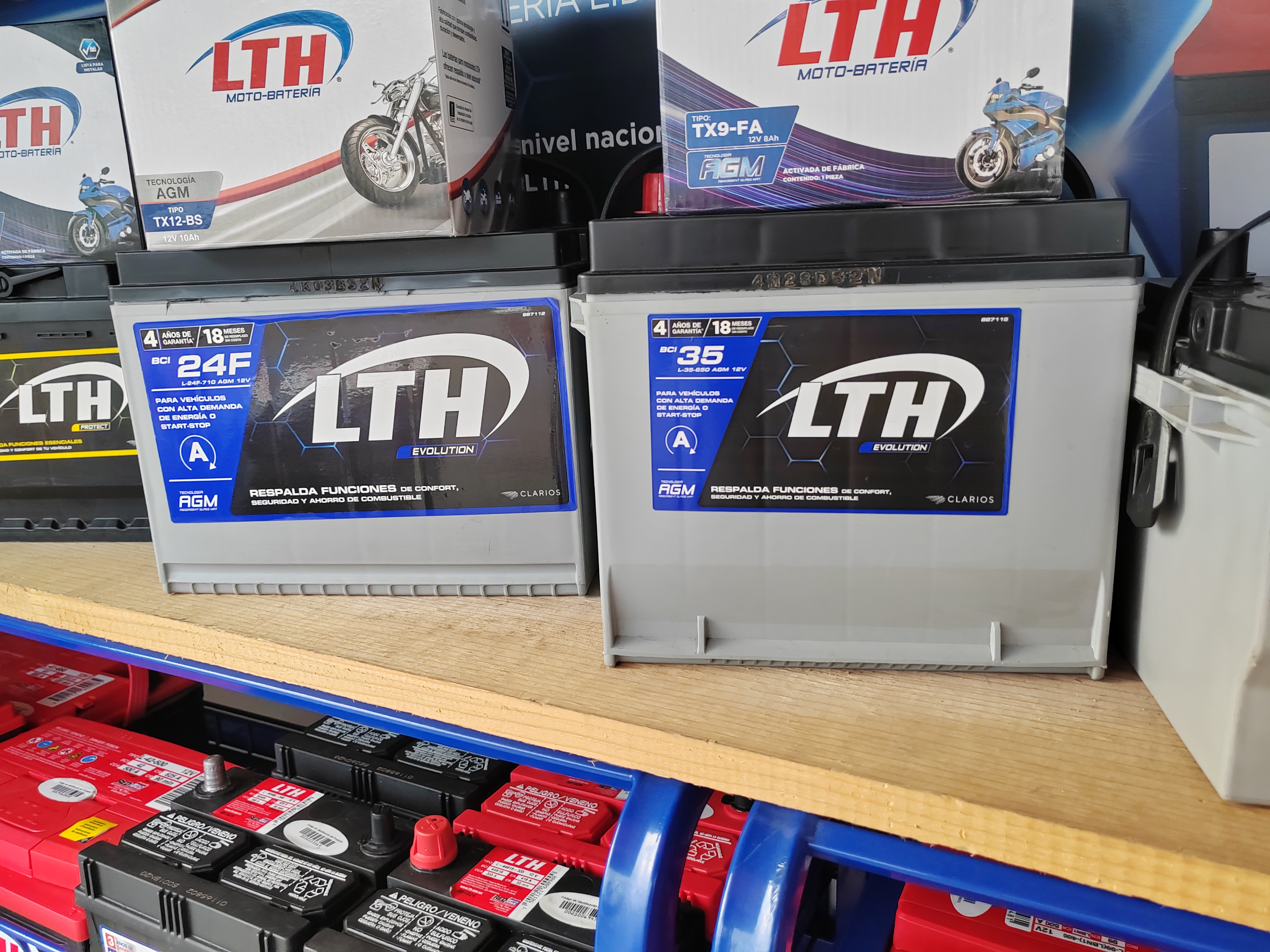 Batería de automóvil en taller mecánico con fondo desenfocado y coche deportivo rojo