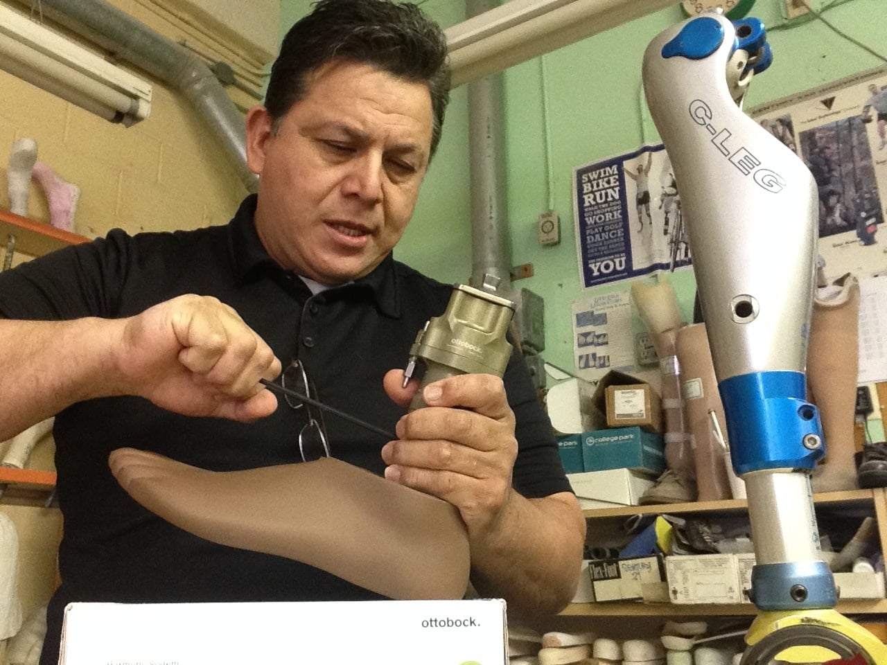 Prosthetist adjusting prosthetic leg components in an orthotics workshop