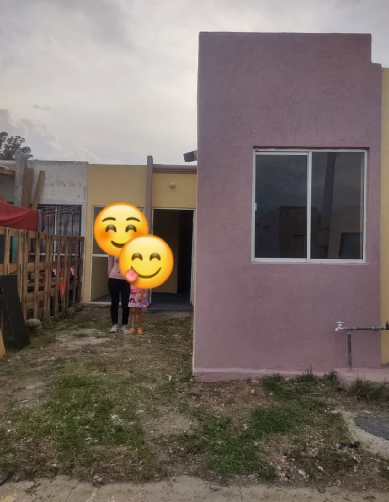 Casa moderna de dos pisos con grandes ventanales y terraza, rodeada de vegetación y palmeras.