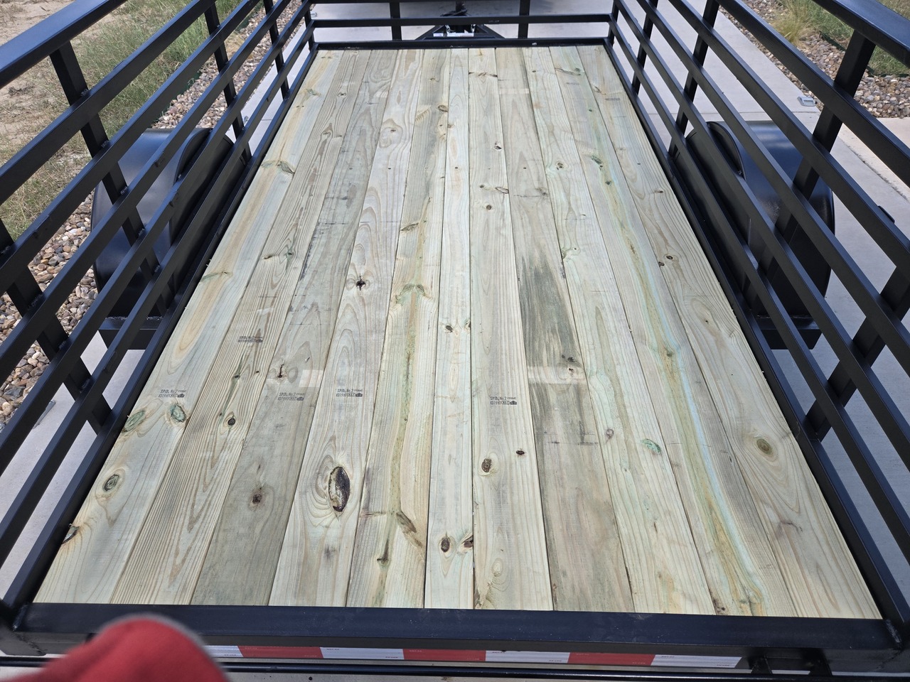 Heavy-duty utility trailer with wooden deck inside a spacious warehouse.