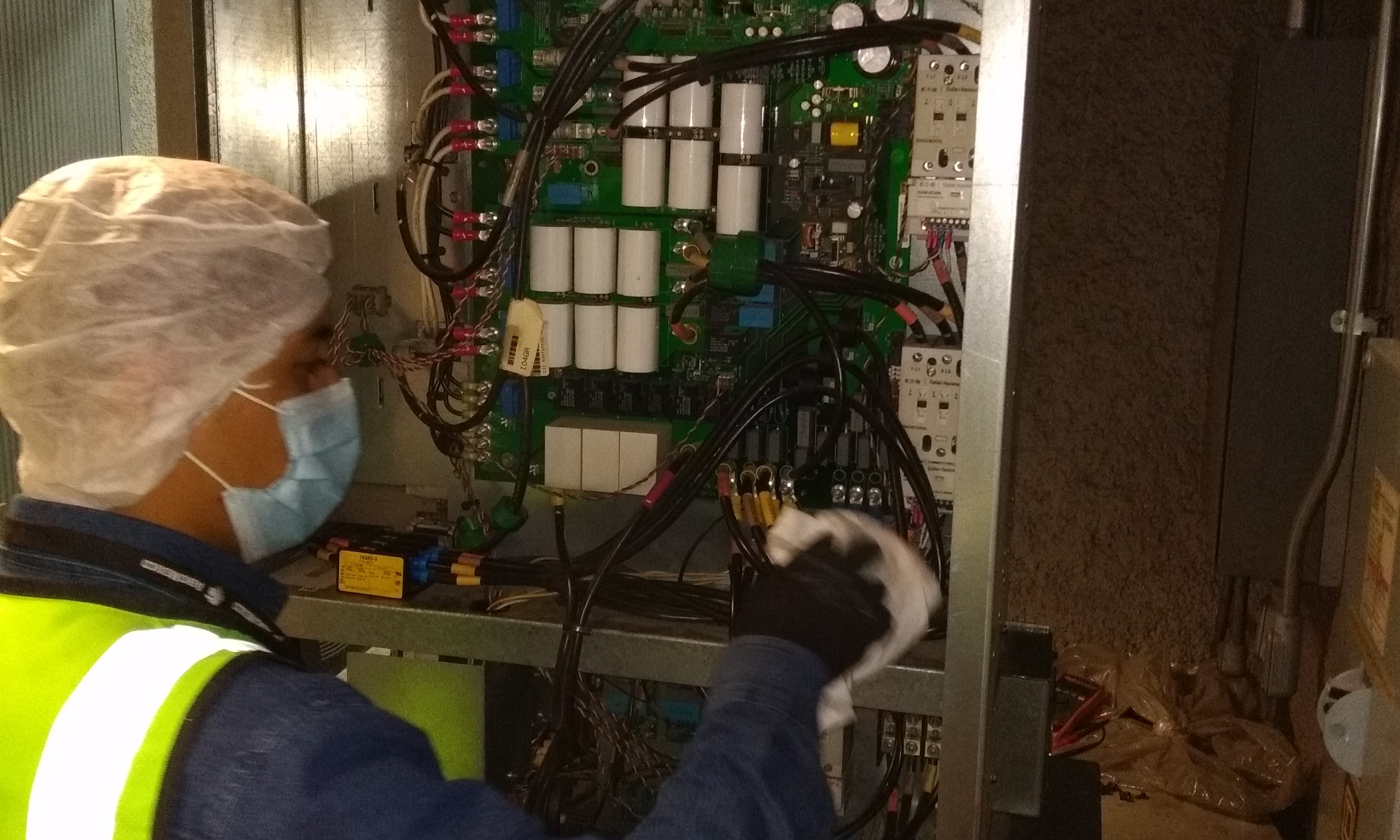 Technician holding a circuit board in front of a laptop
