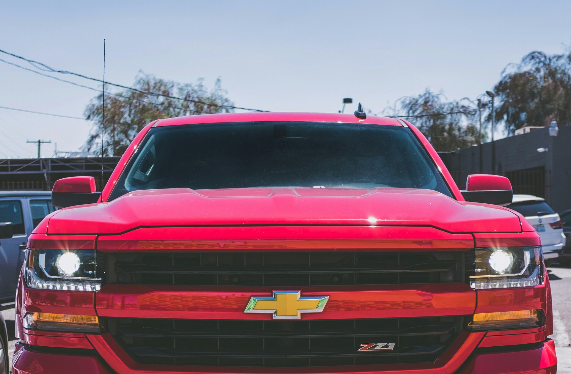 Front view of a red Chevrolet truck with headlights on and the iconic logo visible.