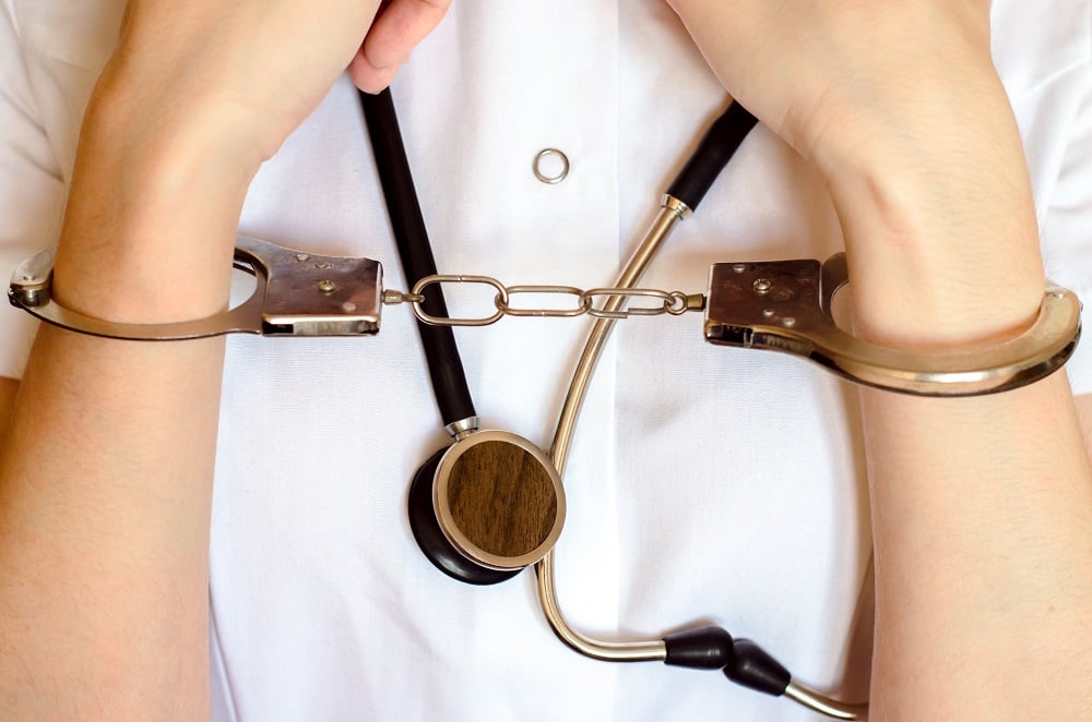 Cuffed doctor wearing stethoscope