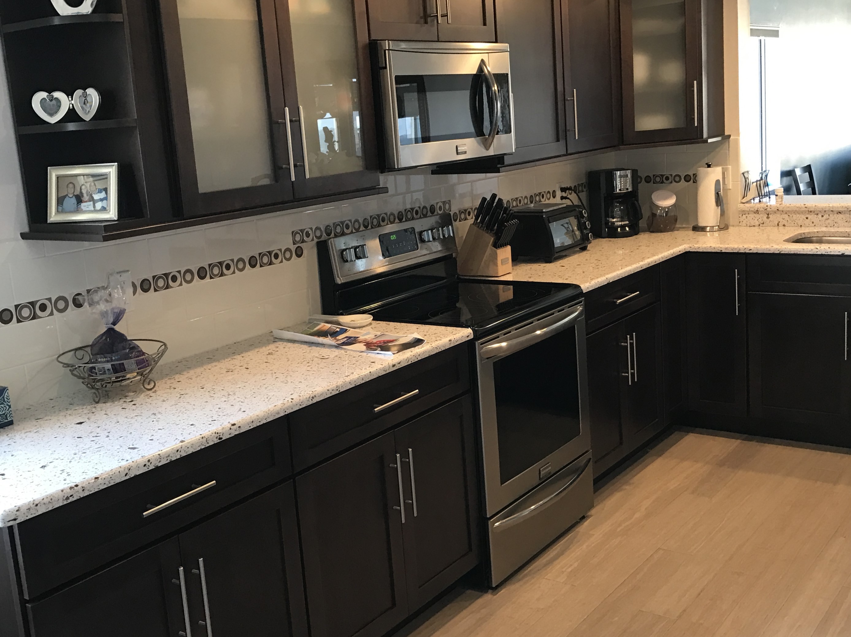 Spacious kitchen featuring painted cabinetry and circular patterned backsplash tile with quartz countertops.