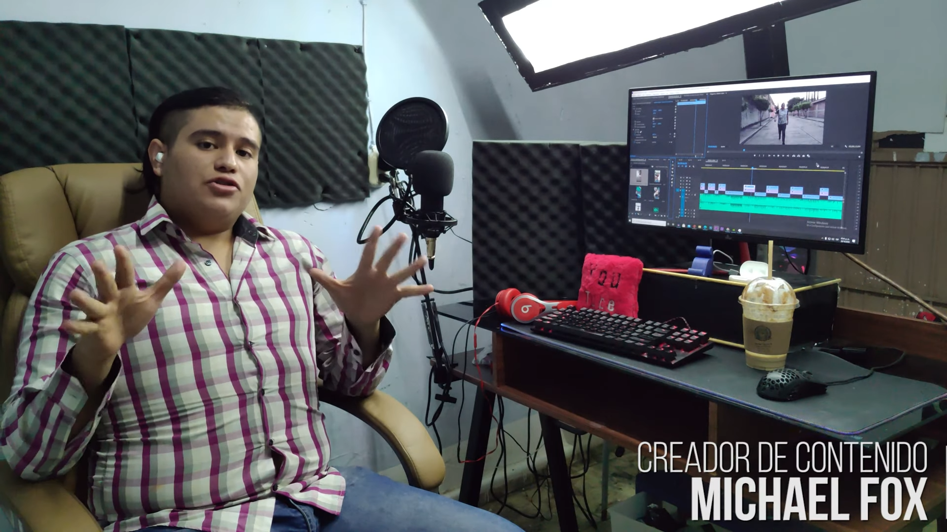 Video production studio with editor at multi-monitor workstation, cameras, lighting, and live streaming setup